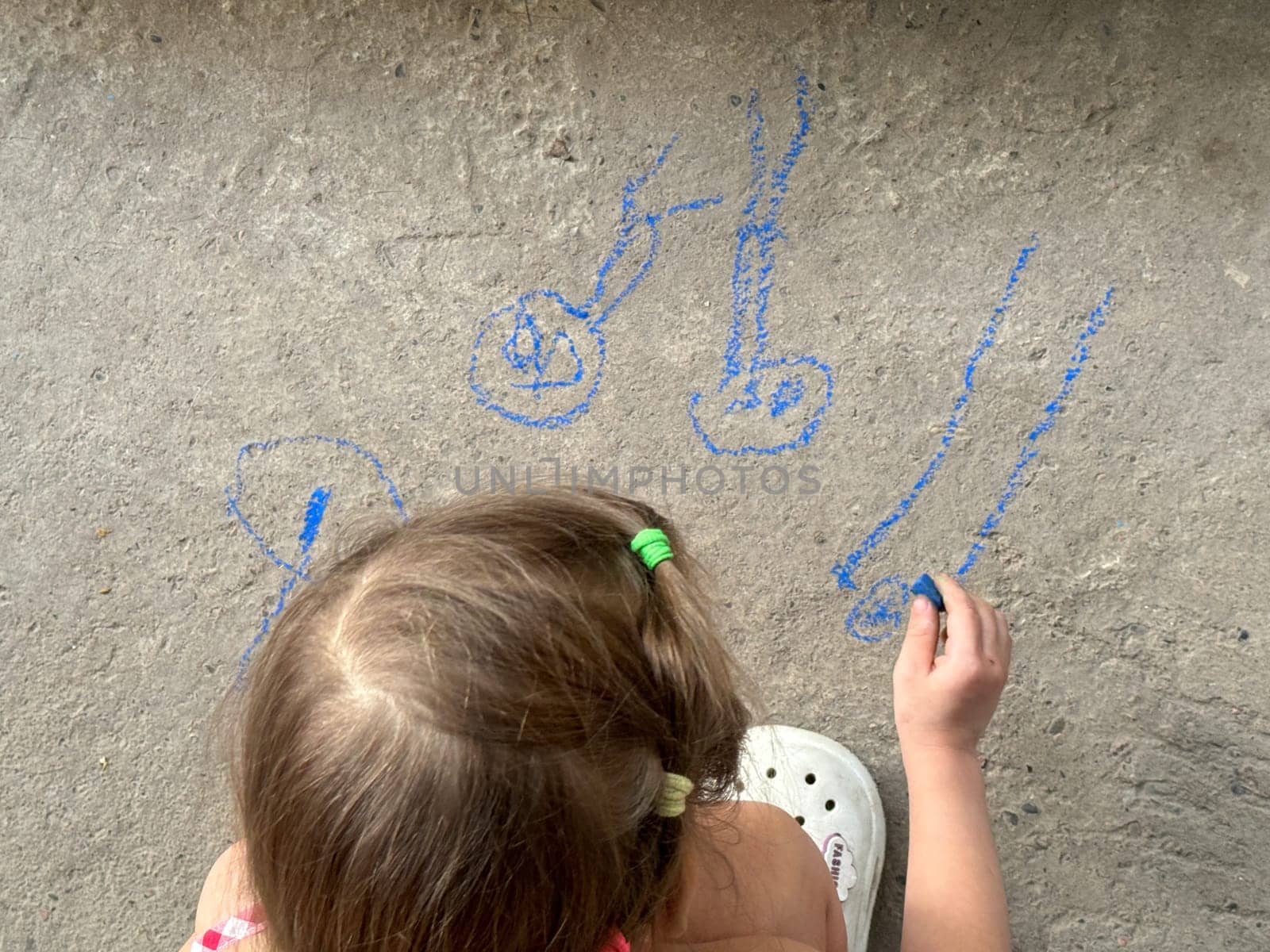 A young child creates a family portrait using bright sidewalk chalk on asphalt. A joyful expression of love, imagination, and childhood creativity