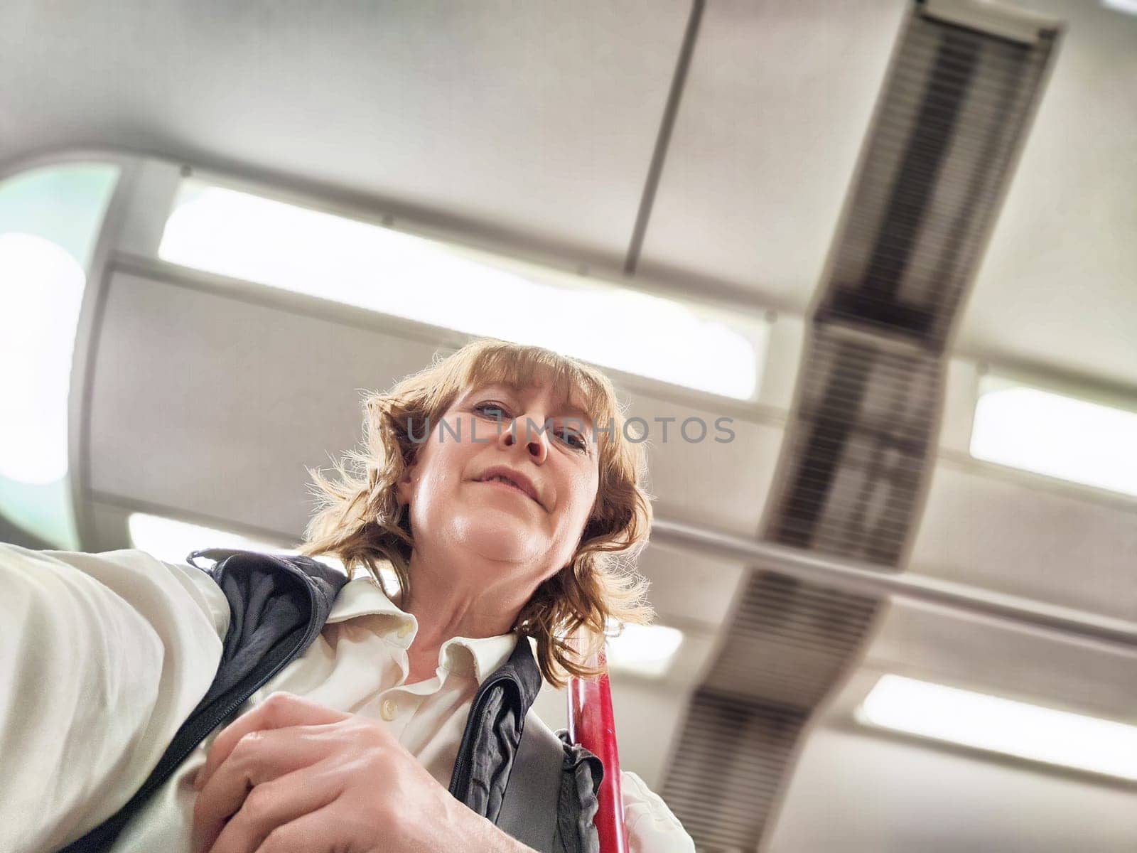 A middle-aged woman takes a selfie on a public transport journey, capturing a moment in her travel adventure.