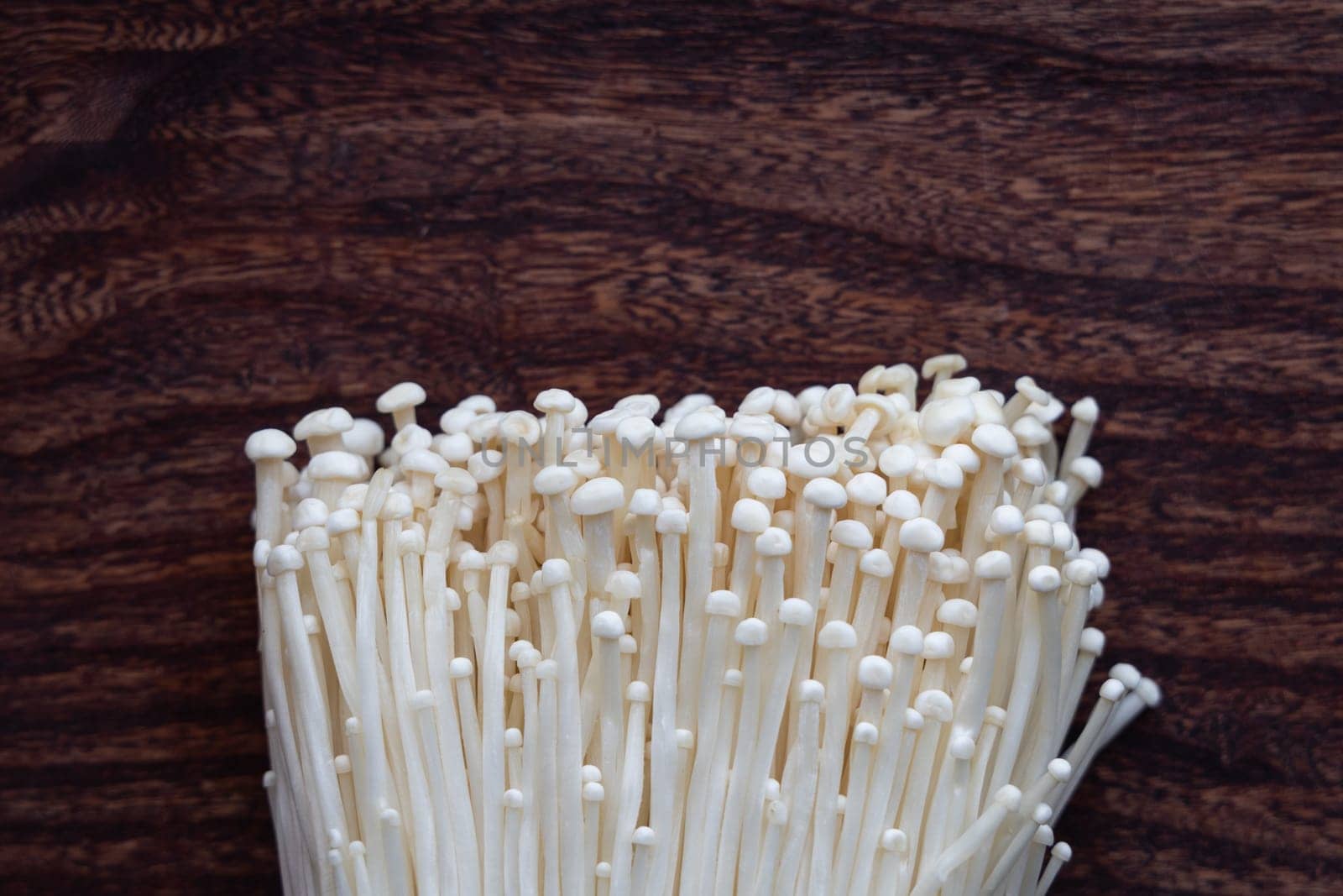 Natural enoki mushrooms close-up on board.