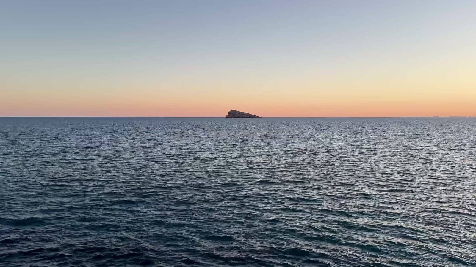 A breathtaking and stunning view of a vibrant sunset illuminating the calm, serene ocean waters and distant mountains