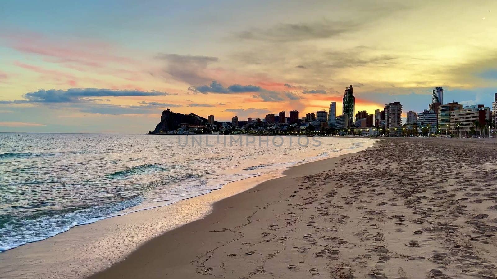 A captivating view of a beach at sunset, featuring a vibrant skyline and gentle waves lapping the shore