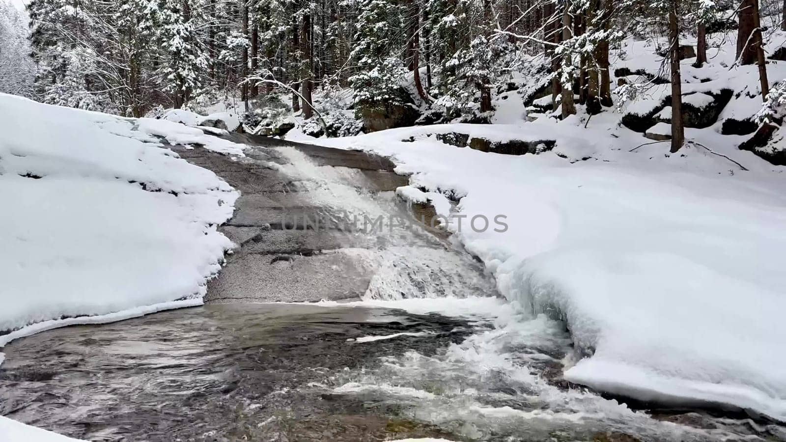 A stunning winter scene features a serene river amid snowy landscapes and evergreen trees, creating beauty