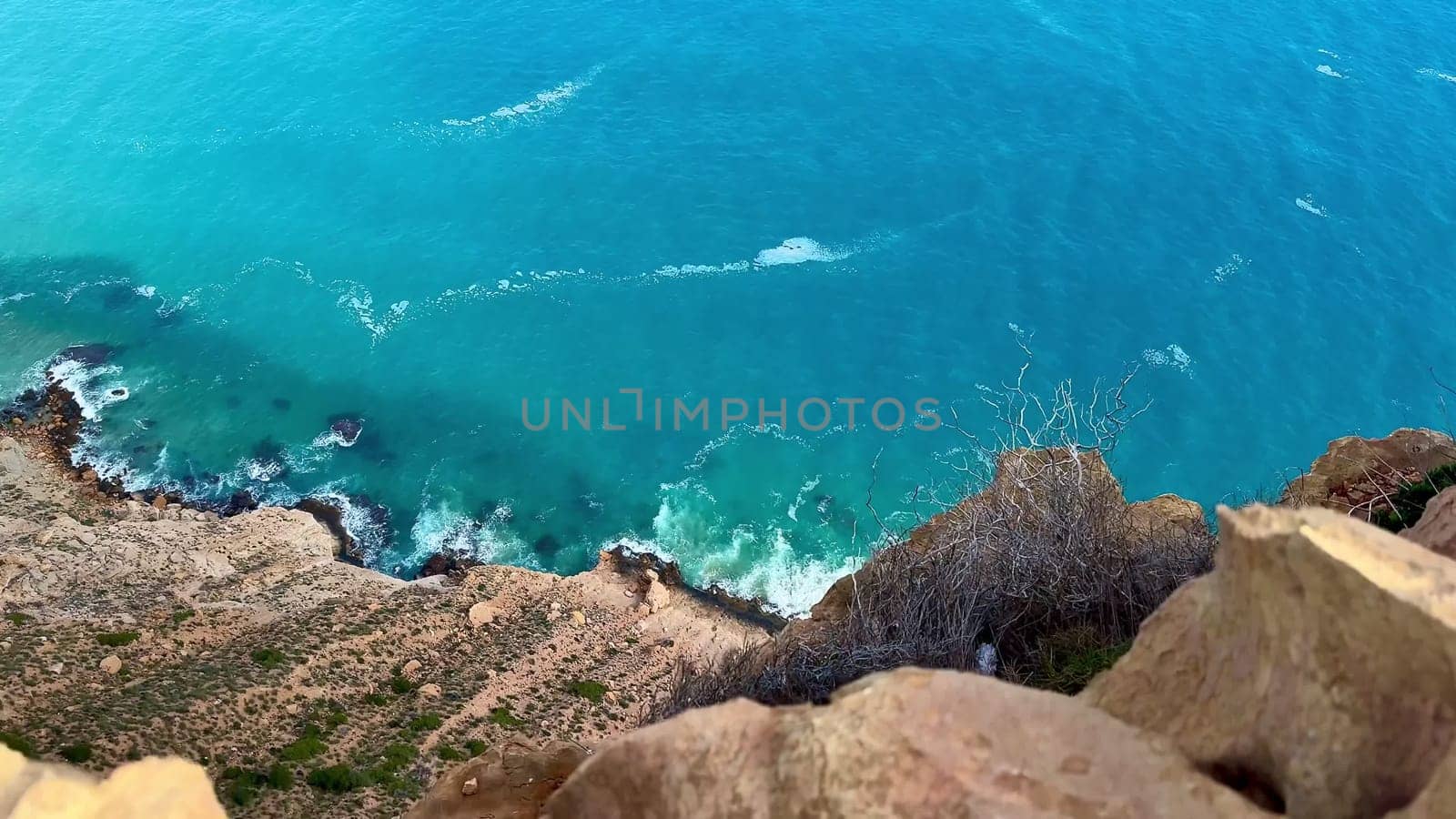 The stunning aerial view shows a turquoise sea blending with rocky cliffs along a peaceful coastline