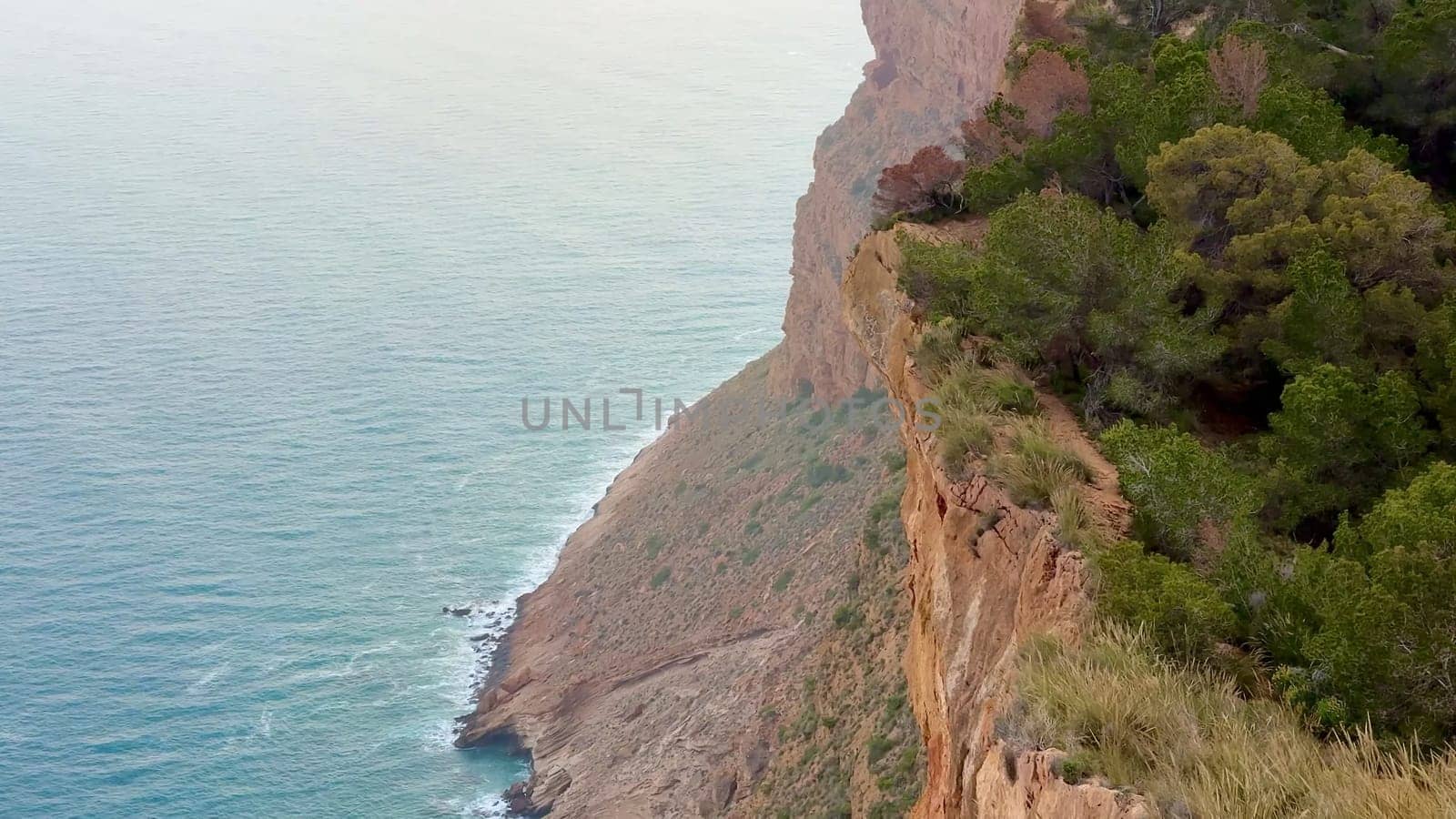 A stunning view of a rugged coastal cliff meeting the calming ocean below, perfect for nature lovers and adventurers