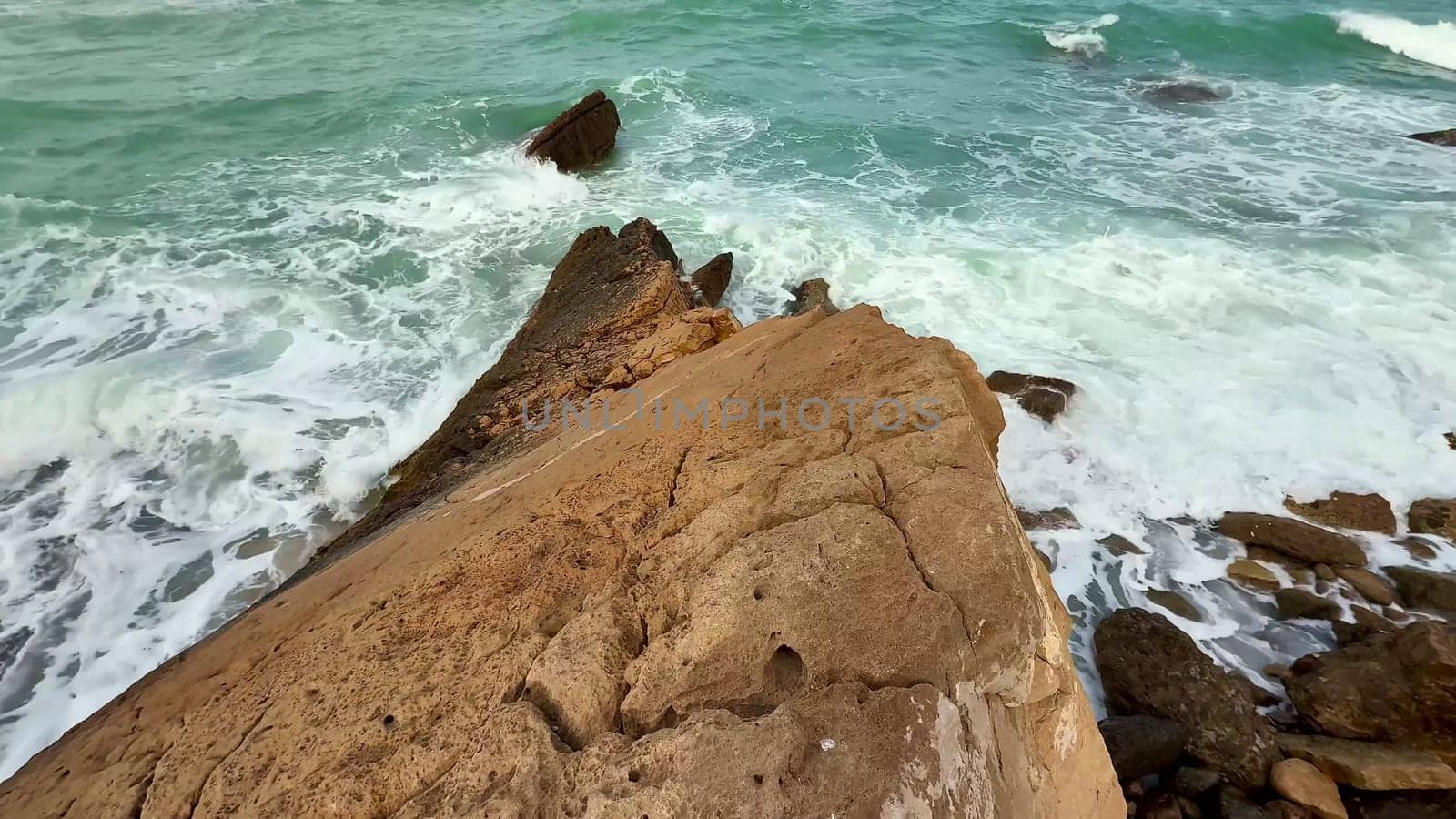 Explore a beautiful rocky coastline where turquoise waves crash against rugged formations, creating a picturesque view