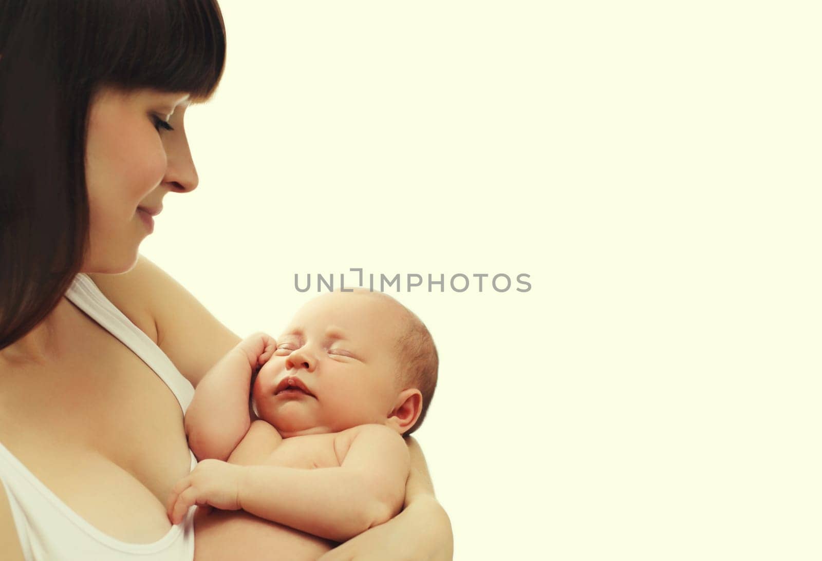 Happy young mother holding cute infant, baby sleeping in arms on white studio background