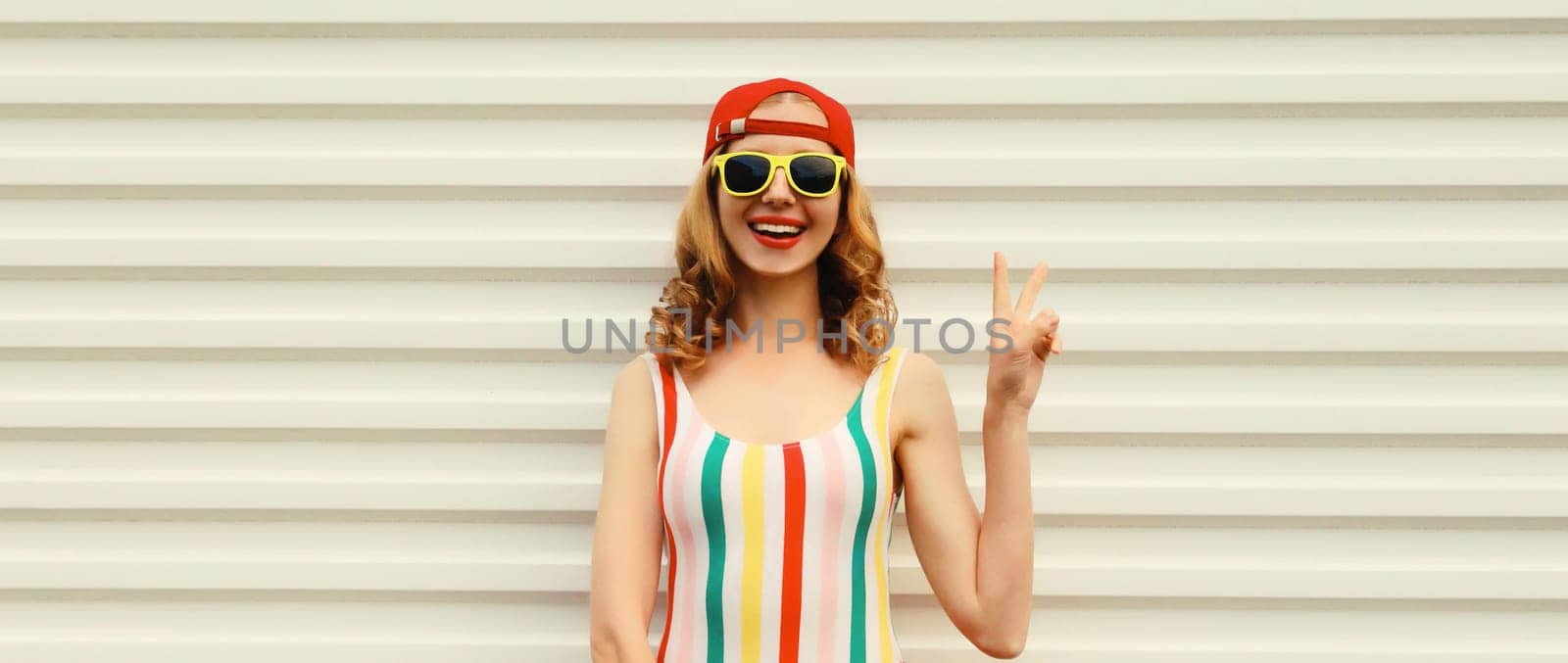 Summer portrait of happy cheerful stylish young woman in colorful clothes with sunglasses, posing on white background