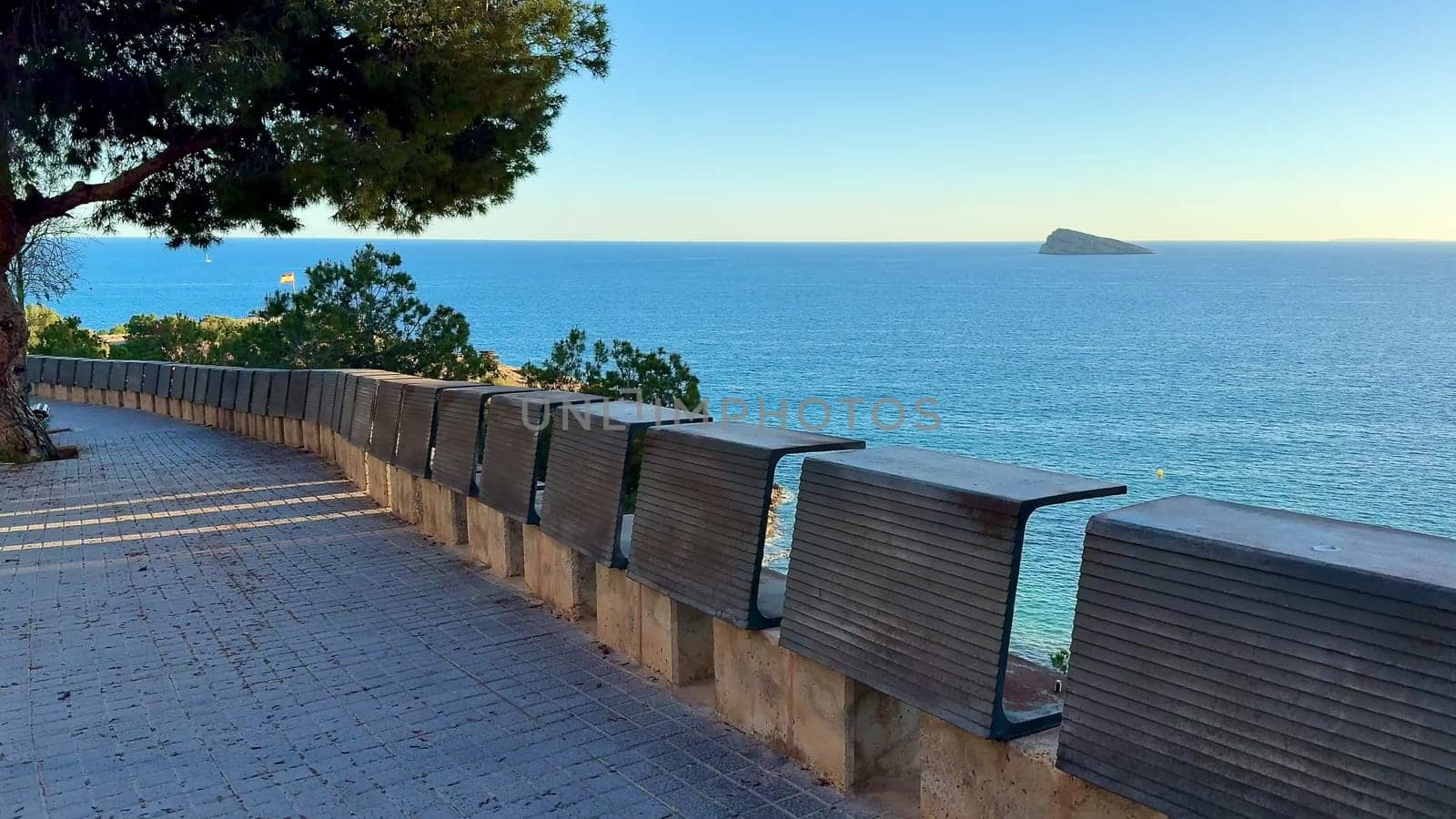 A beautifully serene coastal path that overlooks the tranquil, vast ocean and a distant, picturesque island