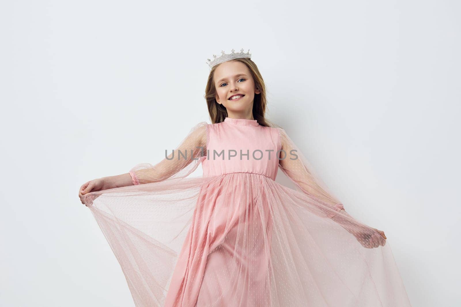 Joyful girl wearing a pink tulle dress and crown, radiating happiness in a minimalistic setting, perfect for childhood fashion, celebrations, and joyful moments