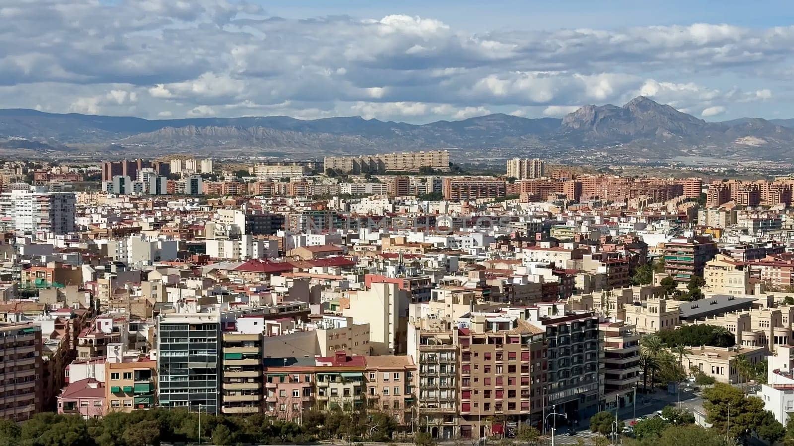 A breathtaking panoramic view of a vibrant urban cityscape, adorned with majestic mountains rising in the background