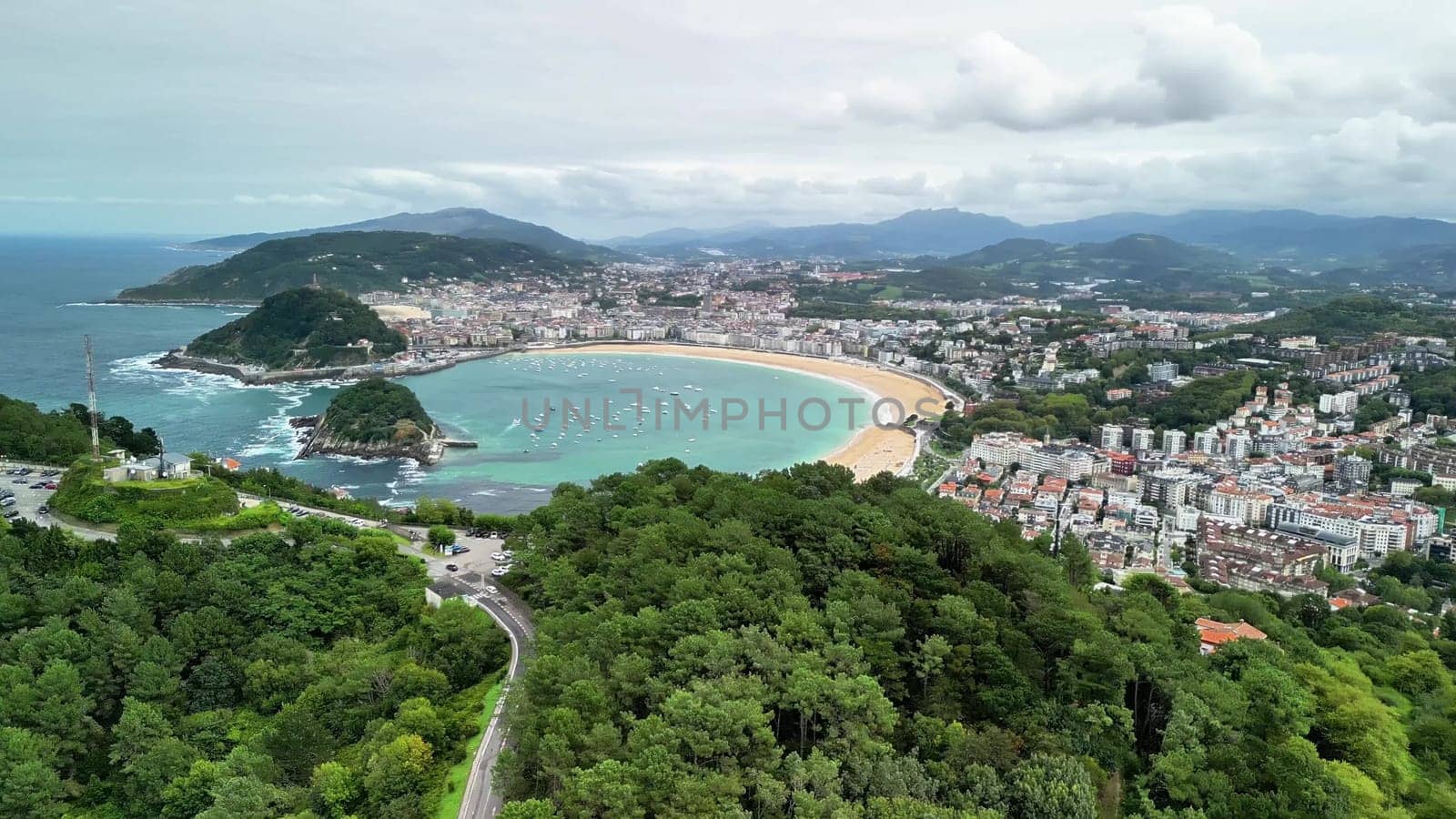 An aerial photograph showcases a stunning beach, a vibrant cityscape, and lush green hills in harmony