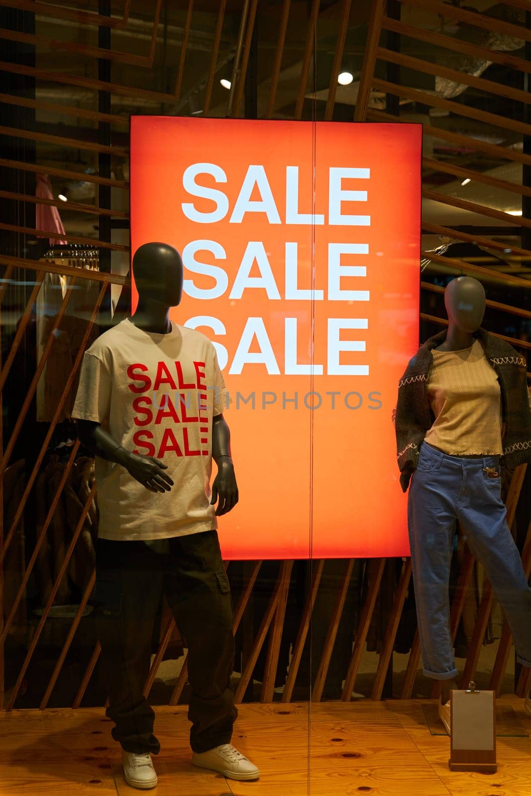 Illuminated shop window with mannequins and a sign saying Sale