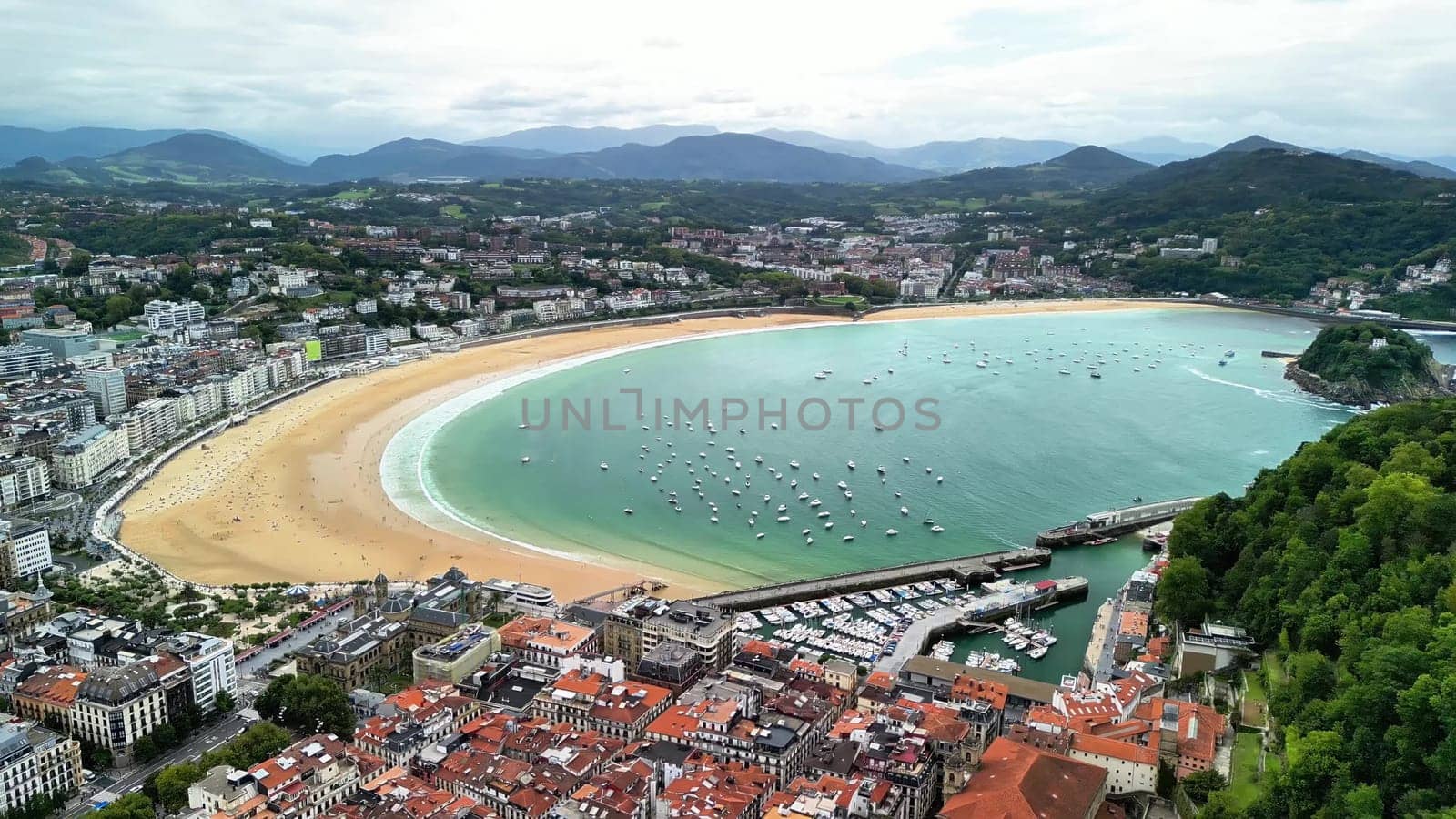 This stunning aerial capture of La Concha Beach showcases its vibrant waters along with a scenic urban backdrop