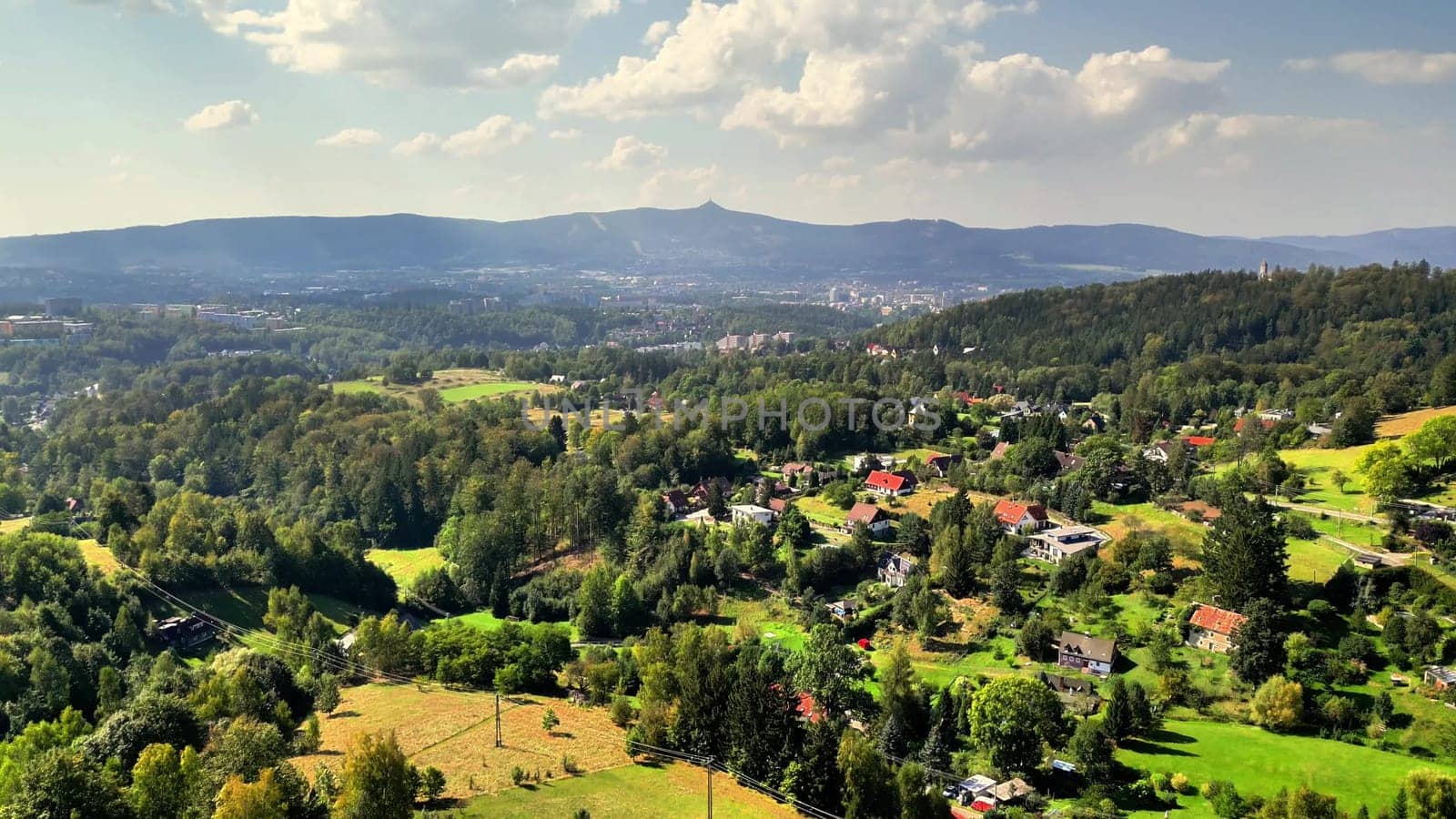 A stunning view of a green valley, surrounded by hills and charming homes, all under a bright sunny sky