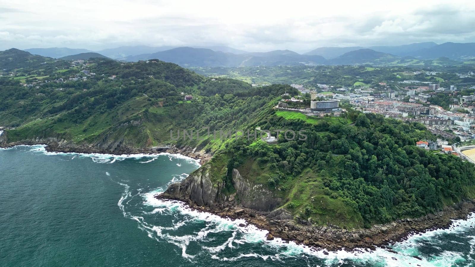 Experience stunning aerial views of lush green hills meeting turquoise waves along the tranquil coast