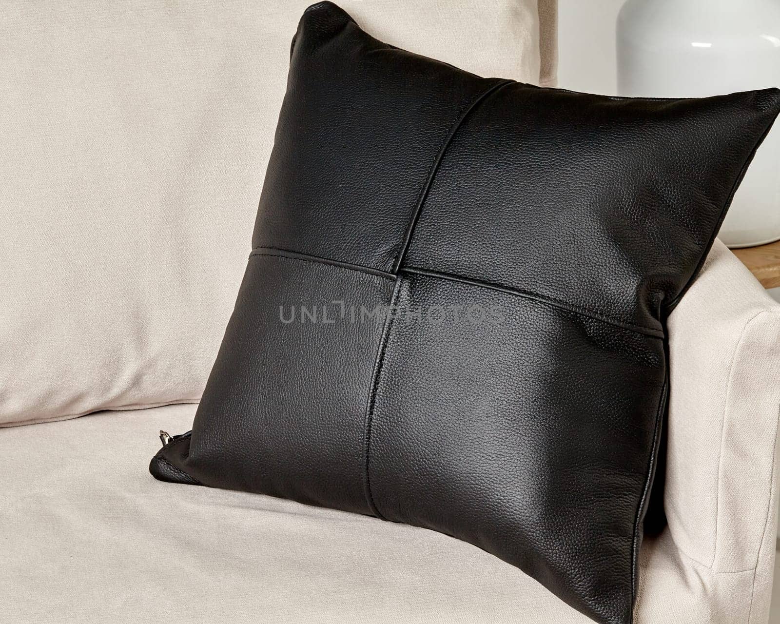 Square black leather cushion adding a touch of elegance to a comfortable beige sofa in a contemporary living room