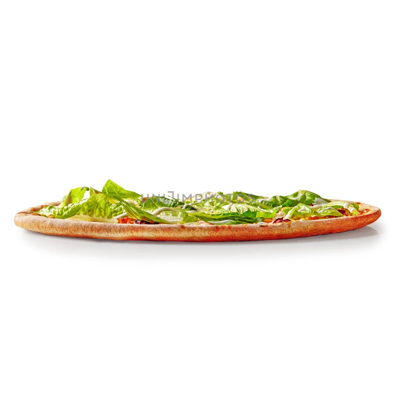 Freshly baked caesar salad pizza featuring romaine lettuce and creamy dressing, isolated on a white background