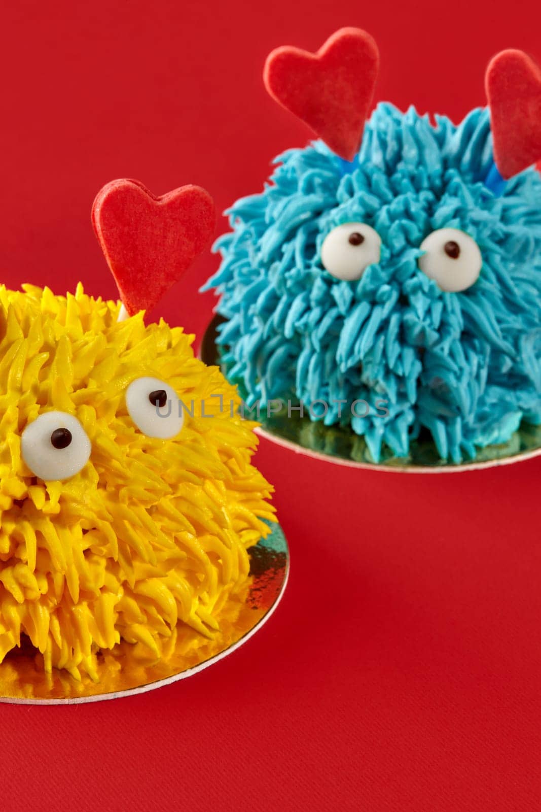 Two funny monster cakes with heart-shaped decorations are showing love and celebrating valentine's day