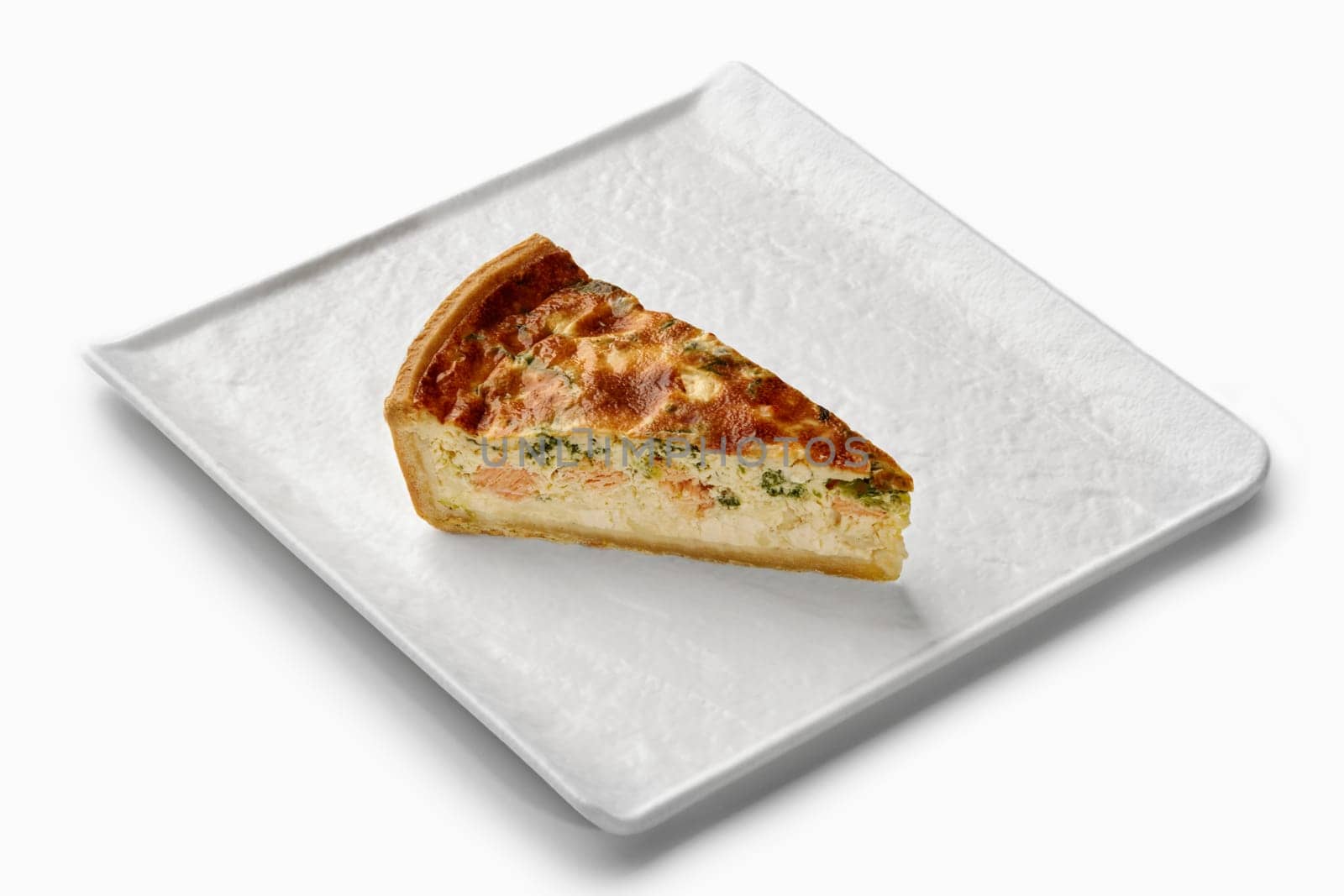 Savory quiche slice featuring salmon, broccoli, and a creamy filling, served on an elegant white plate