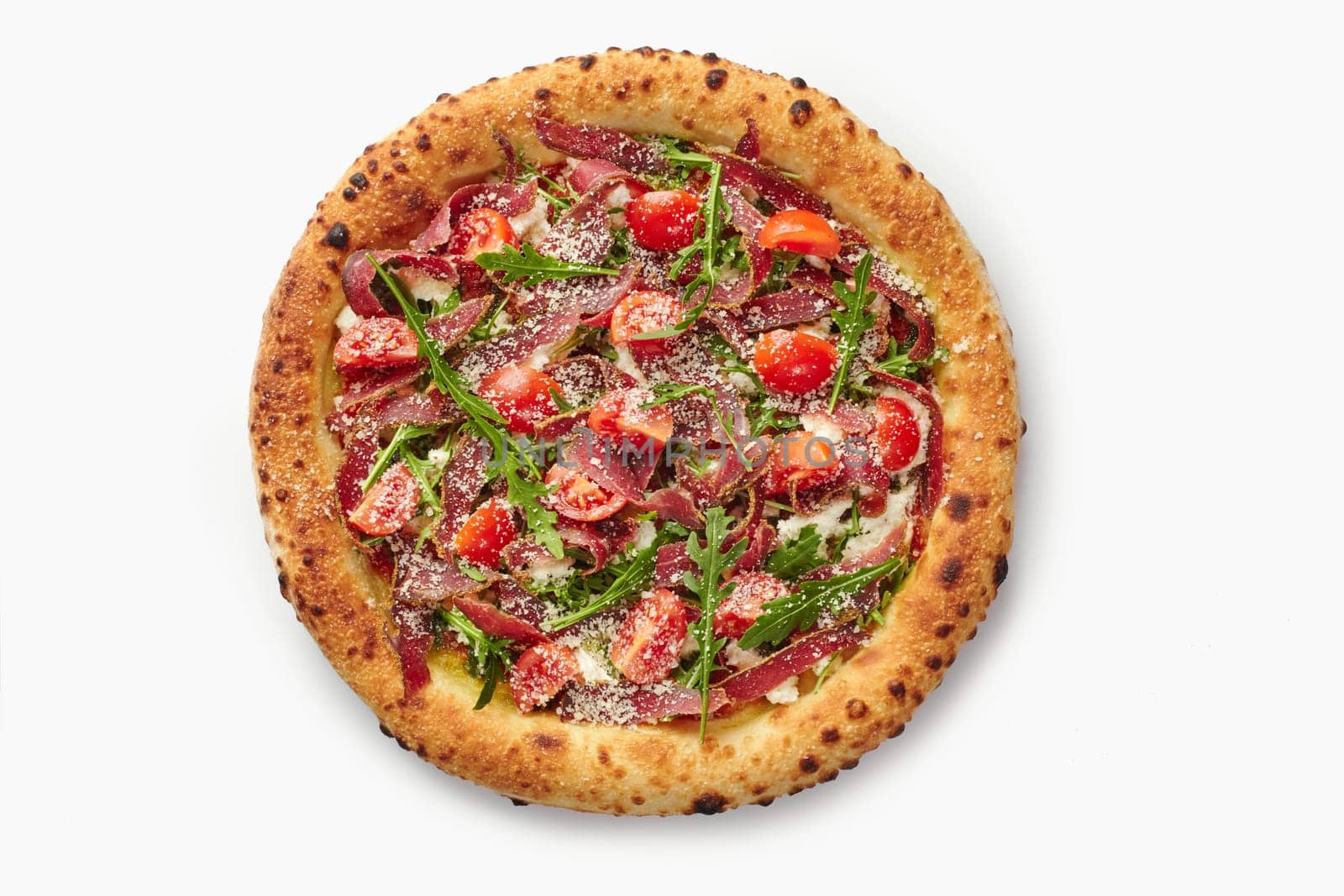 Top view of appetizing pizza with bresaola, cherry tomatoes, arugula and parmesan cheese, creating a vibrant culinary masterpiece