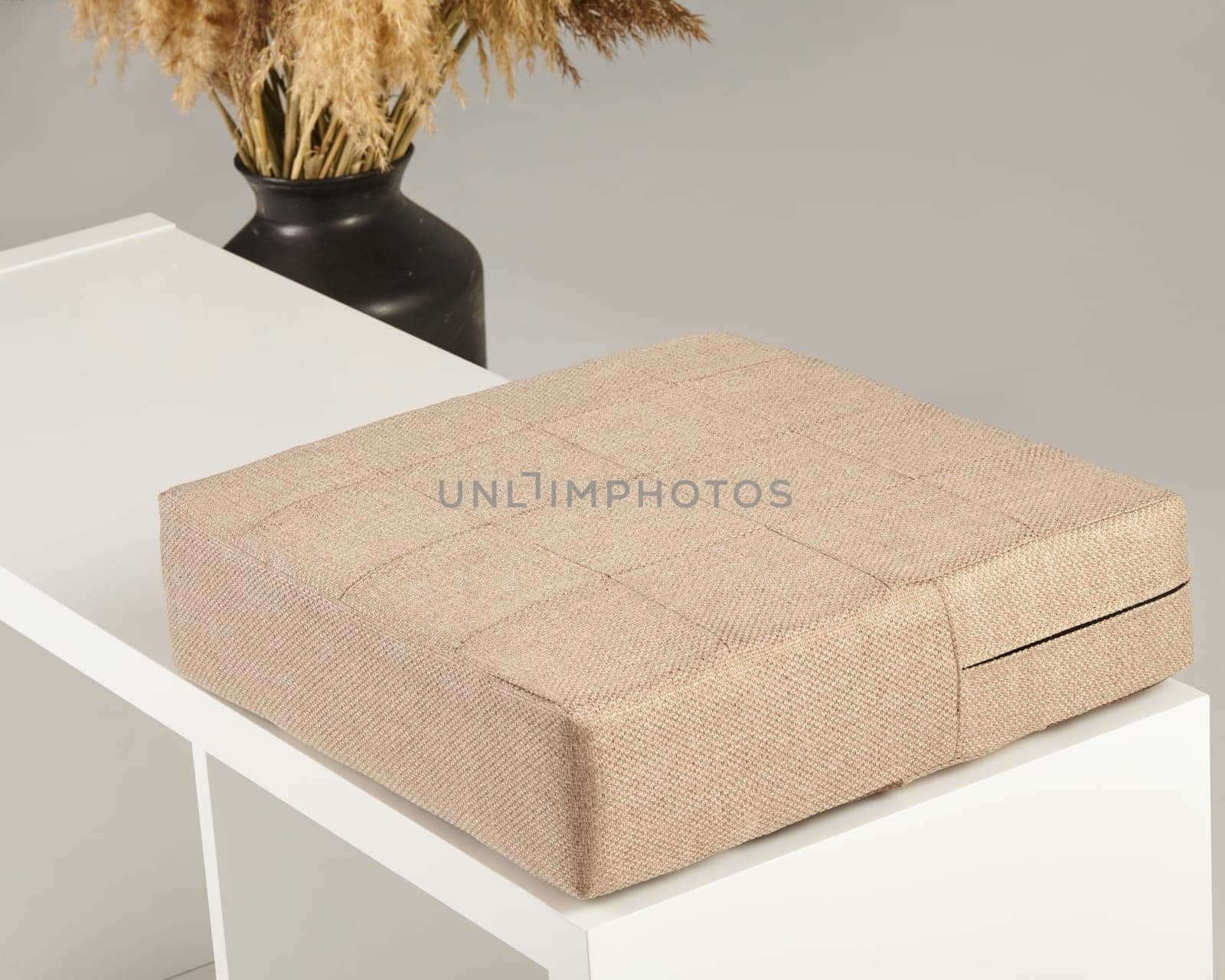 Comfortable beige cushion placed on a white bench, creating a cozy and inviting seating area