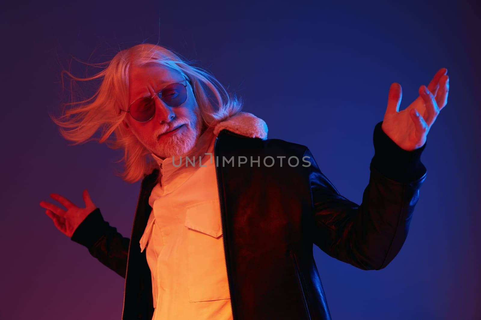 A fashionable man with long white hair and sunglasses stands confidently, dressed in a black leather jacket, set against a vibrant blue and red background, exuding a dynamic and modern vibe