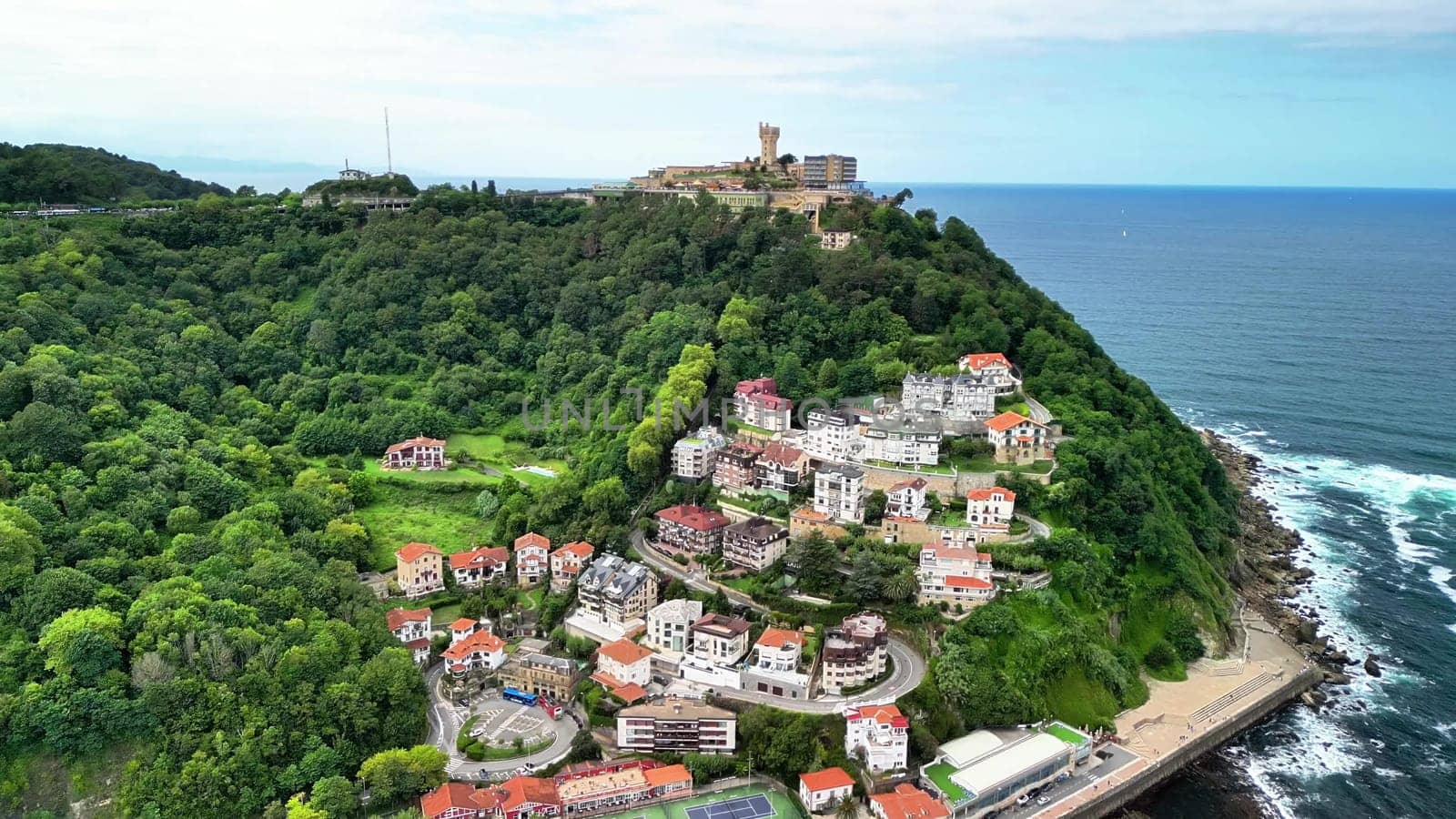 Aerial view showcases a charming coastal village, surrounded by vibrant greenery and the shimmering ocean