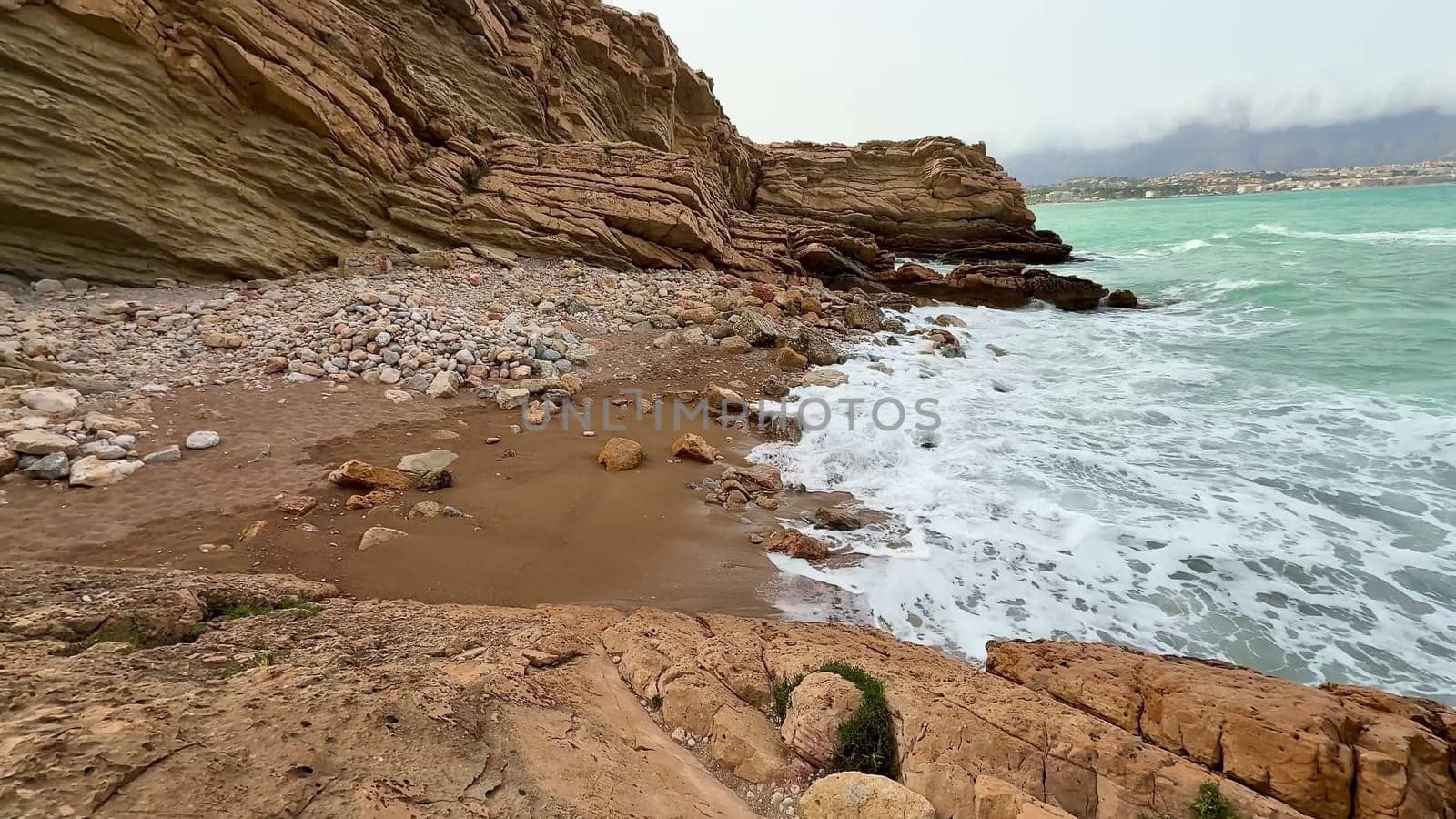 A truly beautiful rocky beach featuring crashing waves and stunning turquoise waters on a serene sunny day
