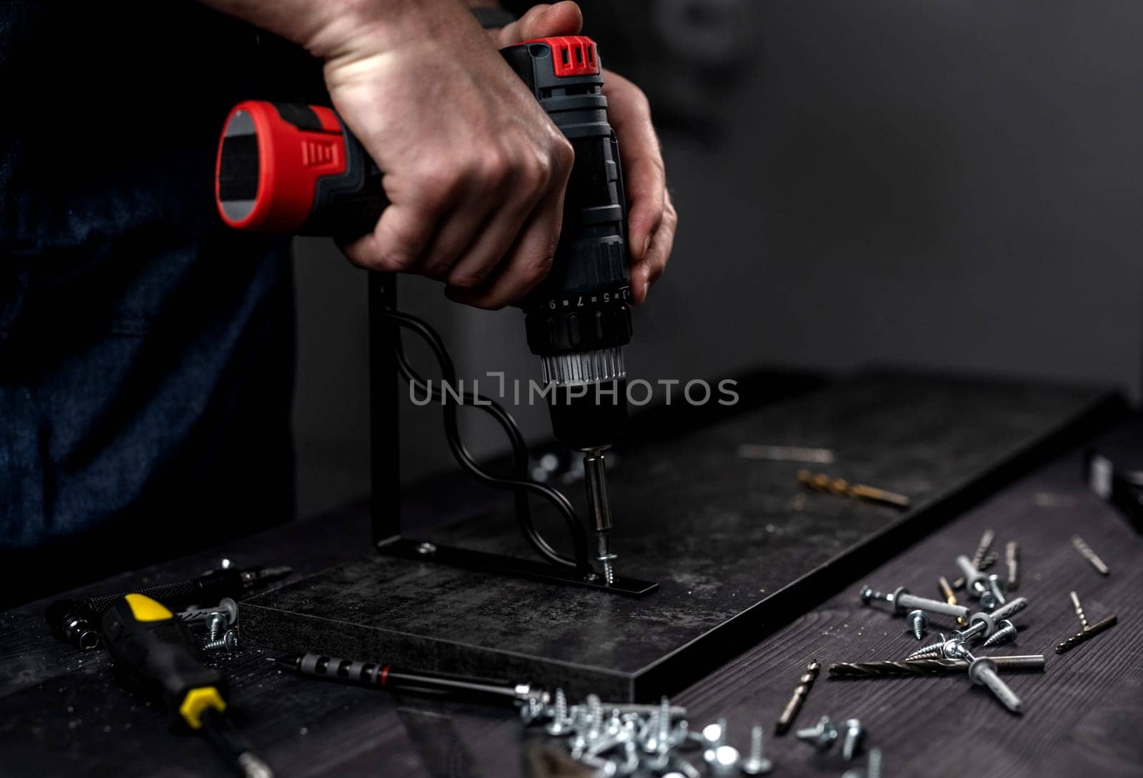 Man Screws Bracket To Shelf With Screwdriver, Hands In Close-Up