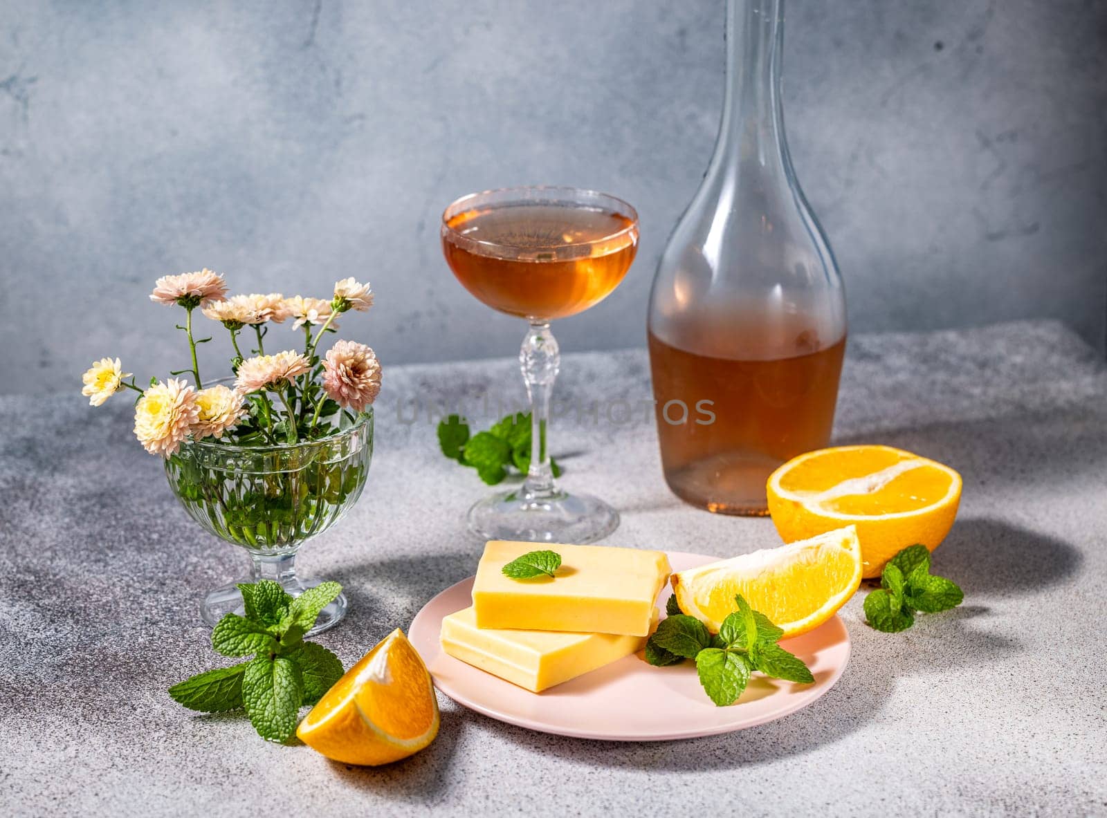 Gourmet setting featuring orange flavored white chocolate bars, a glass and a bottle of wine, orange slices and fresh mint leaves