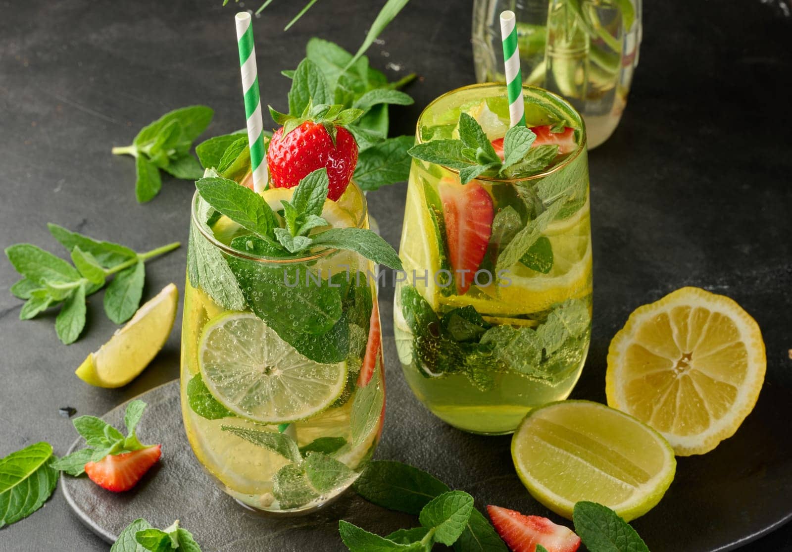 A refreshing drink in a glass with lemon slices, strawberries, fresh mint leaves, and sparkling water