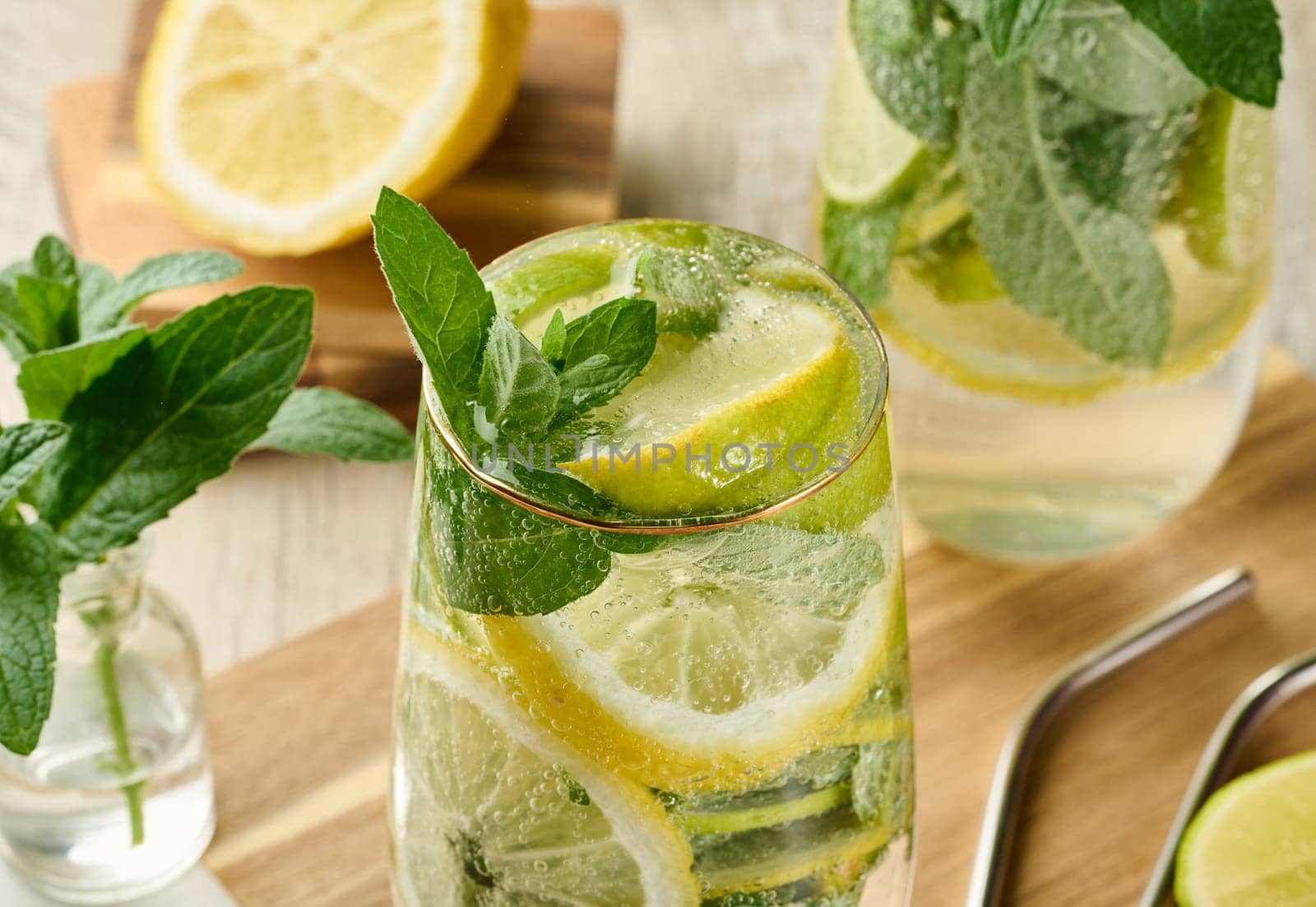 Refreshing citrus and mint drink in glasses with ice, lemon, lime, and mint leaves. Healthy summer beverage