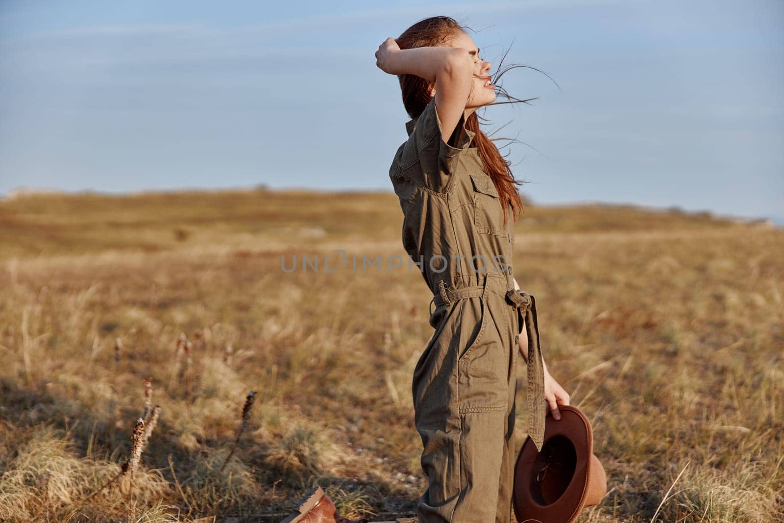 Woman standing in the middle of a field with a hat on her head enjoying the beauty of nature