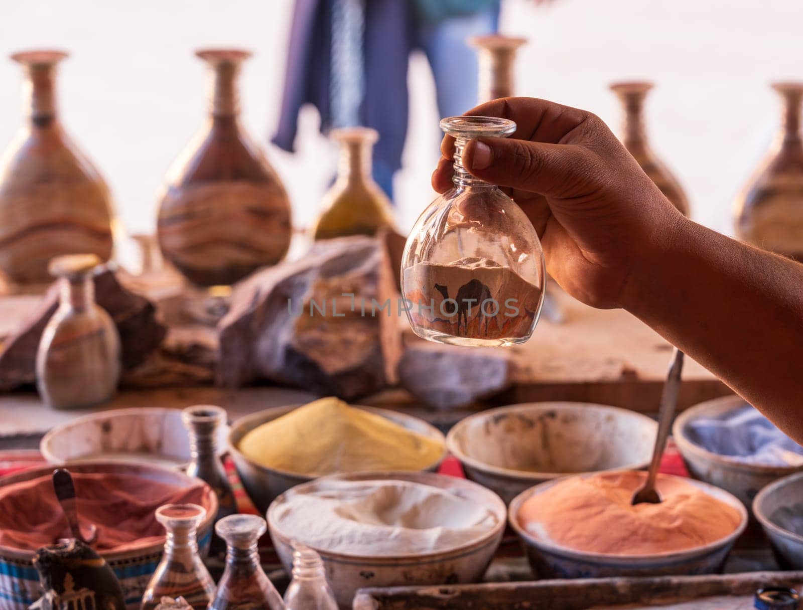 A skilled artisan meticulously crafting a colorful sand bottle souvenir in the ancient city of Petra