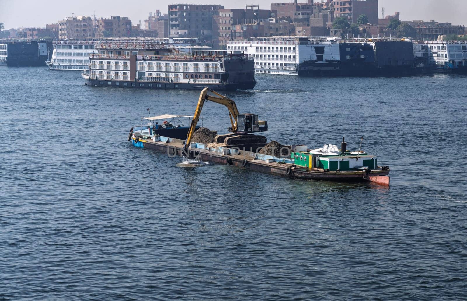 Crowded harbor in Edfu with Nile cruise boats docked and dredging boat removing silt from river