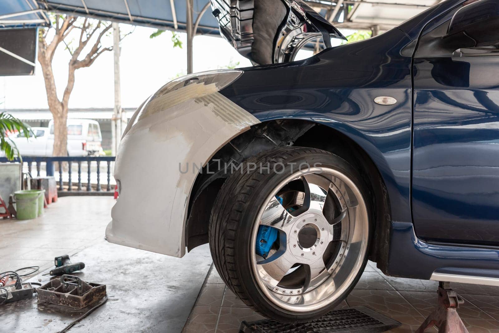 Denter or car mechanic serviceman check and fix body work and fiber bumper body part for fix and repair problem at car garage or repair shop