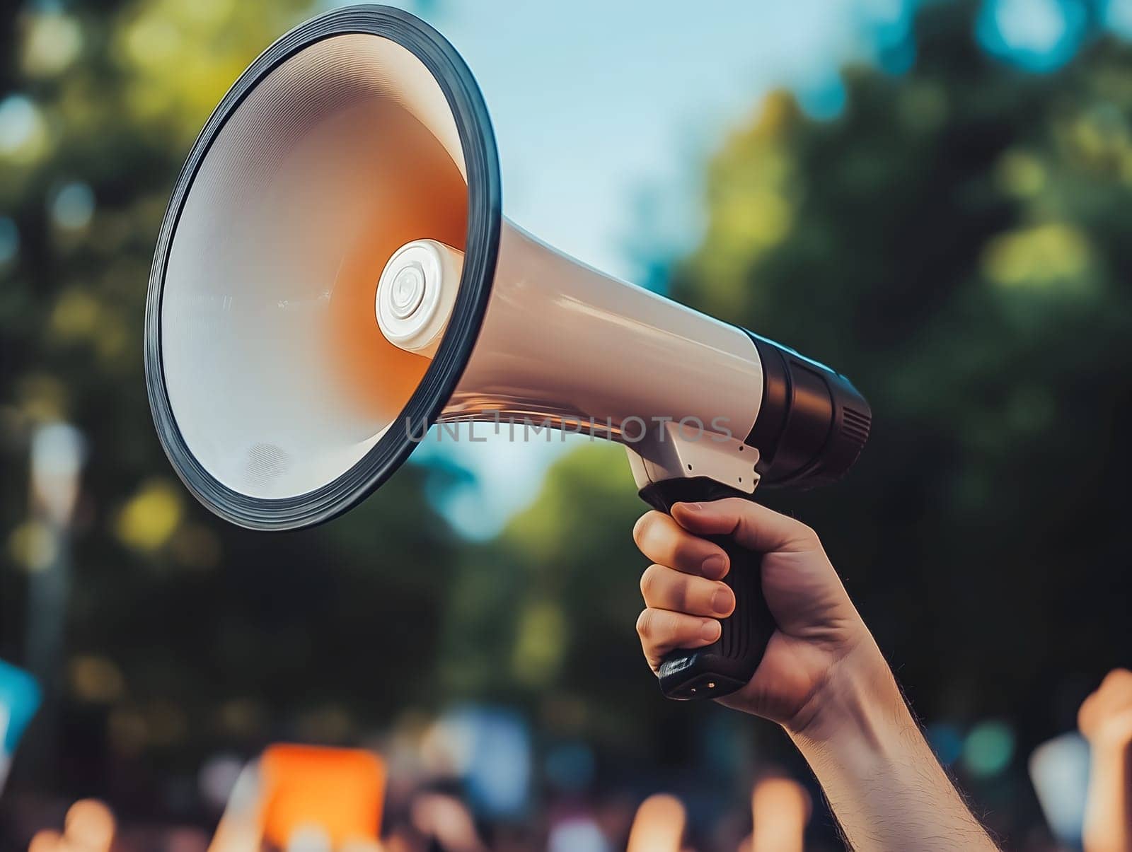 Raised hand holding a megaphone at an outdoor rally or protest with a defocused crowd, symbolizing activism, speech, or social movement, generated by artificial intelligence for communication themes