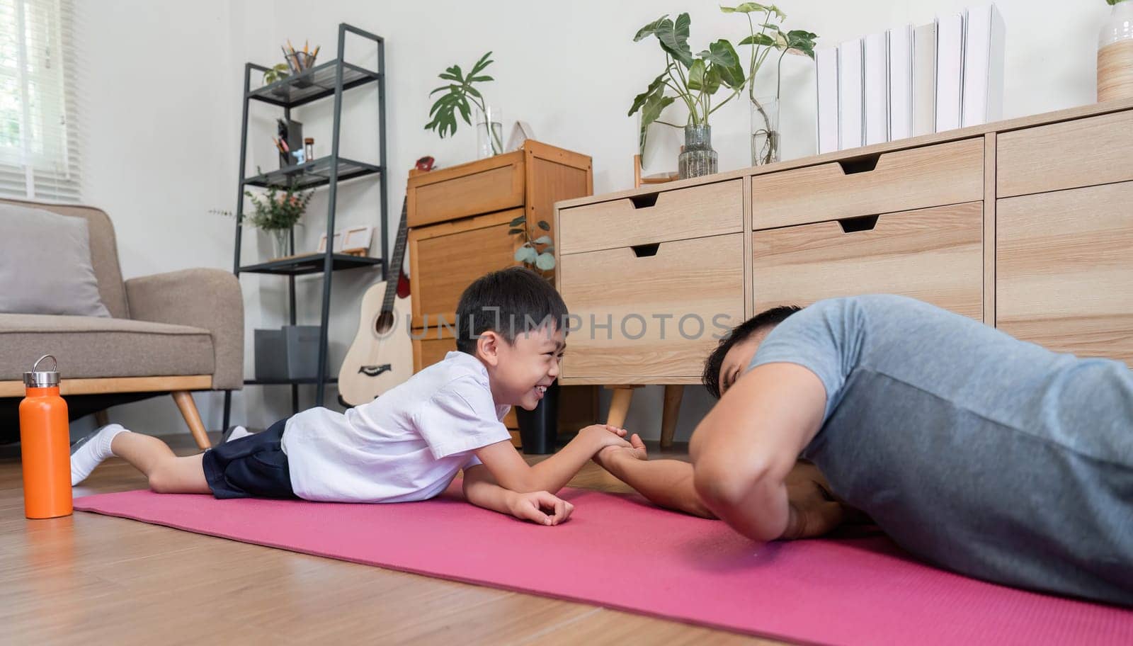 A cheerful father and son enjoy a light-hearted arm wrestling match at home, enhancing their bond and making fitness fun.