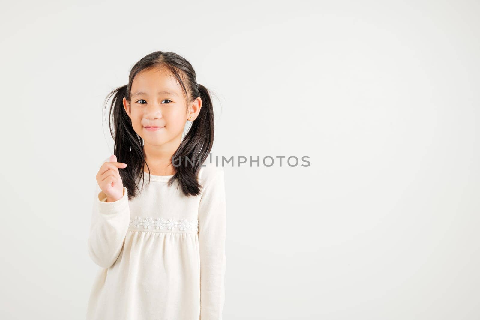 Portrait of happy Asian young kid girl, confidently smiling showing mini heart sign with finger studio shot isolated on white background. Kindergarten child expressing love and joy for Valentine's Day