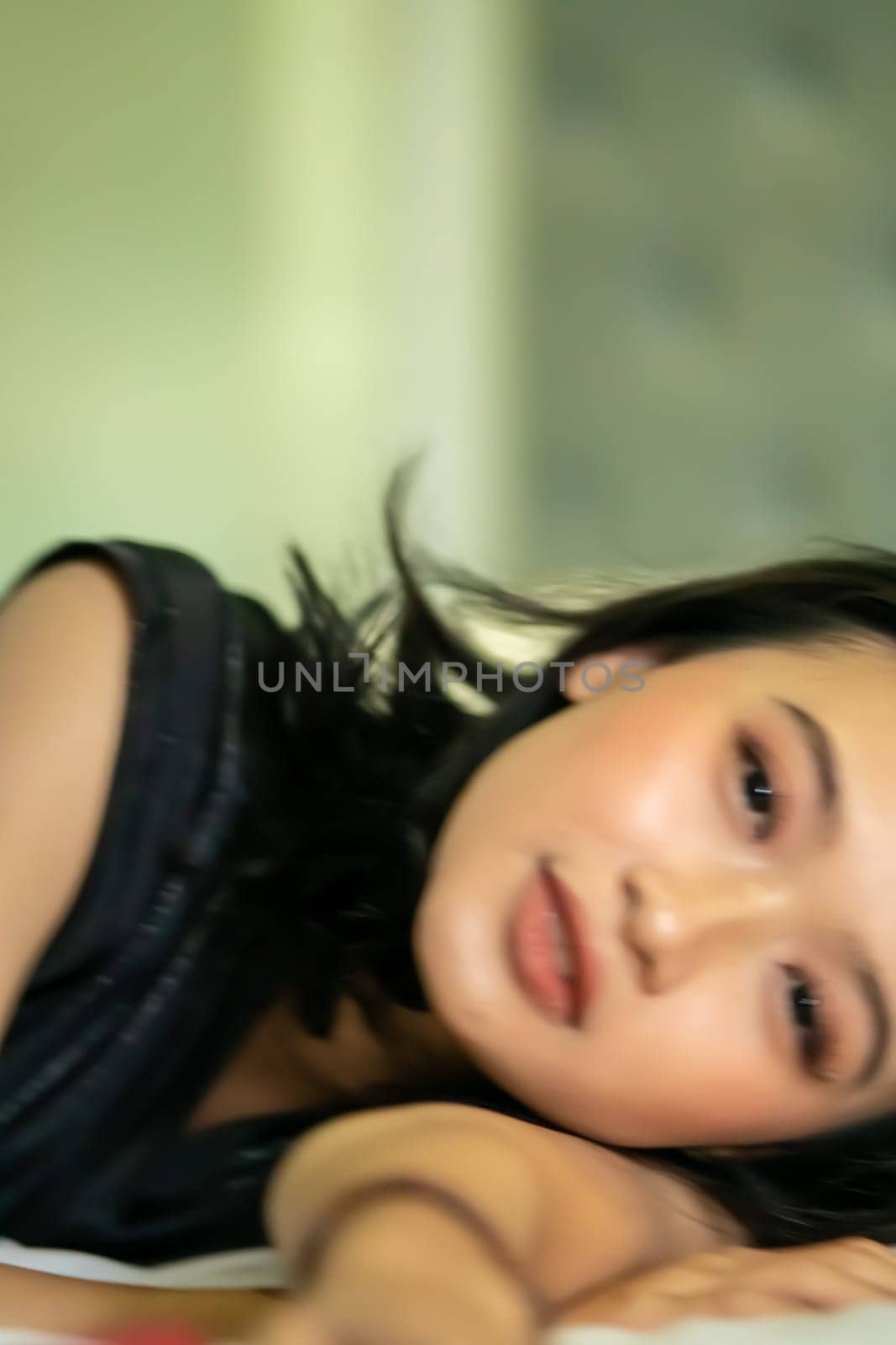 Indonesian women sleeping alone in her bad and she have a black hair while wearing a black dresses