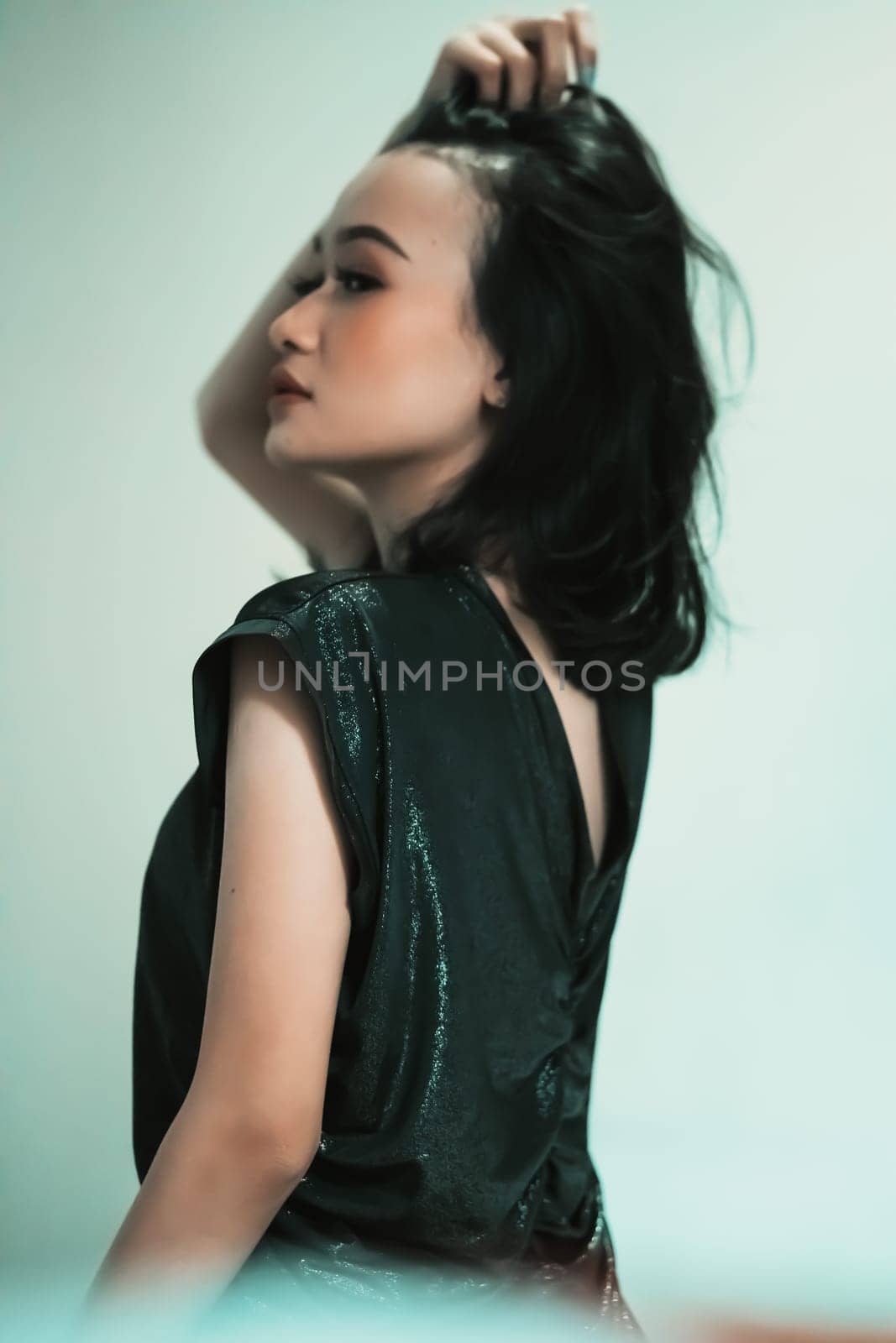 Asian women playing her black hair while wearing black dresses with smiling faces with green background