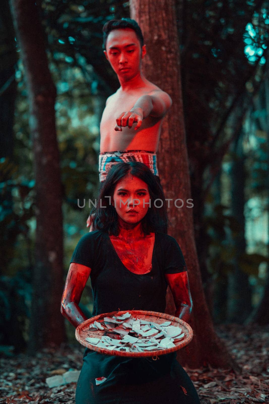 a couple of serial killers have bodies covered in blood and are performing a satanic ritual in the middle of a forest before sunset