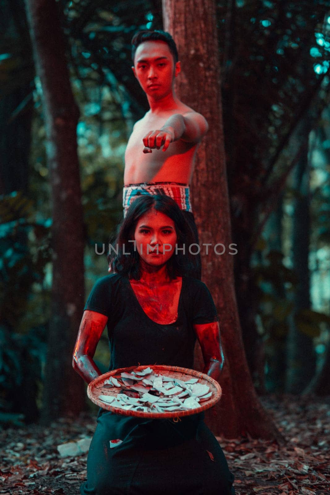 a couple of serial killers have bodies covered in blood and are performing a satanic ritual in the middle of a forest before sunset