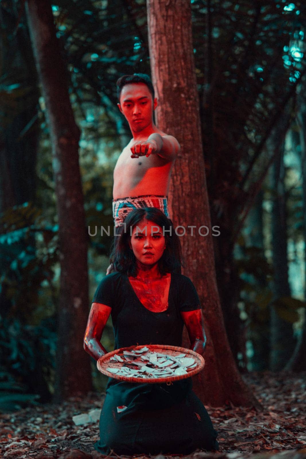 a couple of serial killers have bodies covered in blood and are performing a satanic ritual in the middle of a forest before sunset