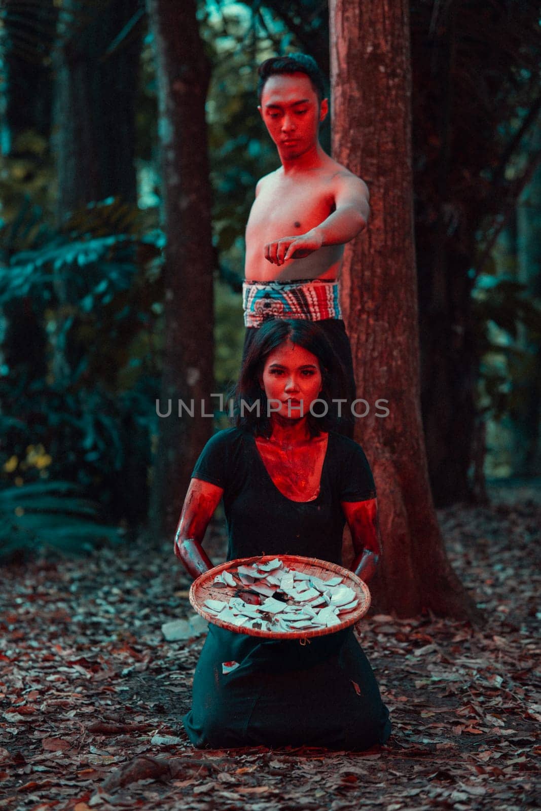 a couple of serial killers have bodies covered in blood and are performing a satanic ritual in the middle of a forest before sunset