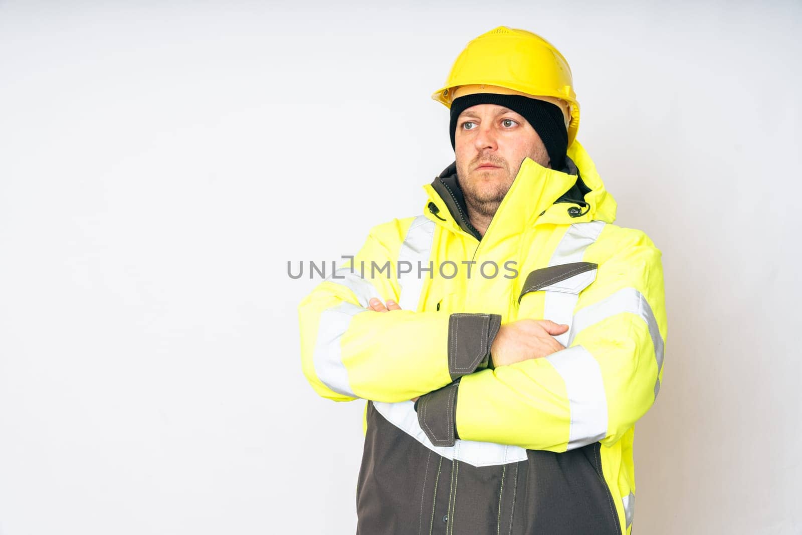 a man wearing a yellow working winter jacket and a yellow safety helmet . High quality photo