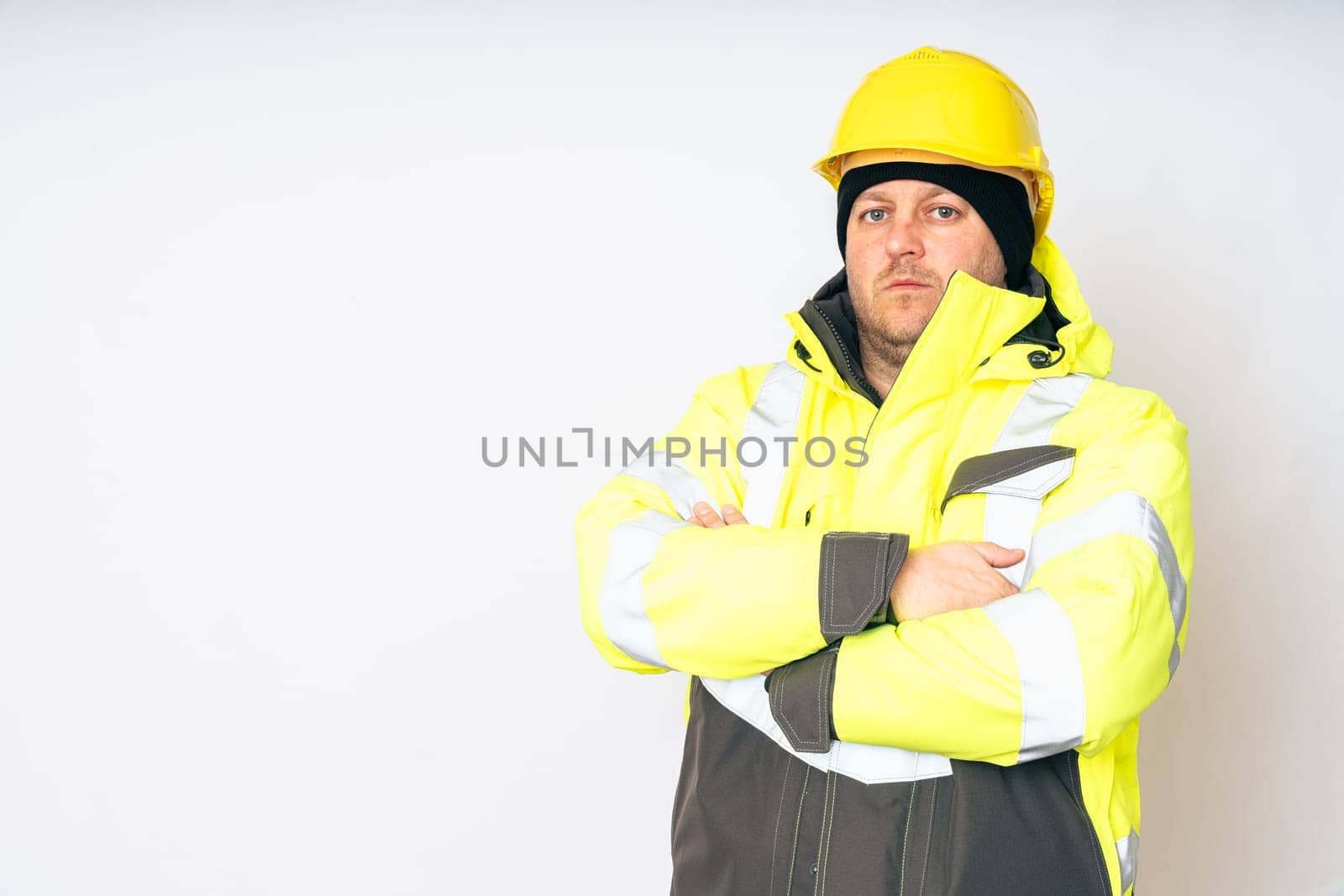 a man wearing a yellow working winter jacket and a yellow safety helmet . High quality photo
