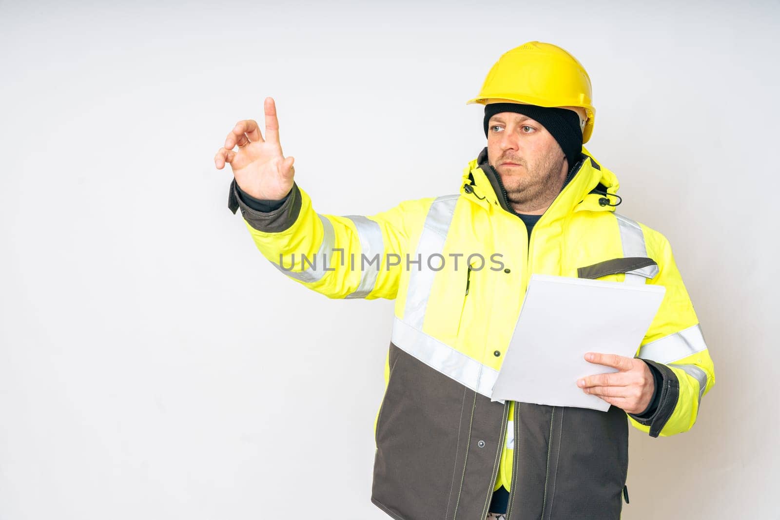 a man in a yellow working winter jacket, yellow safety helmet with papers in his hands. High quality photo