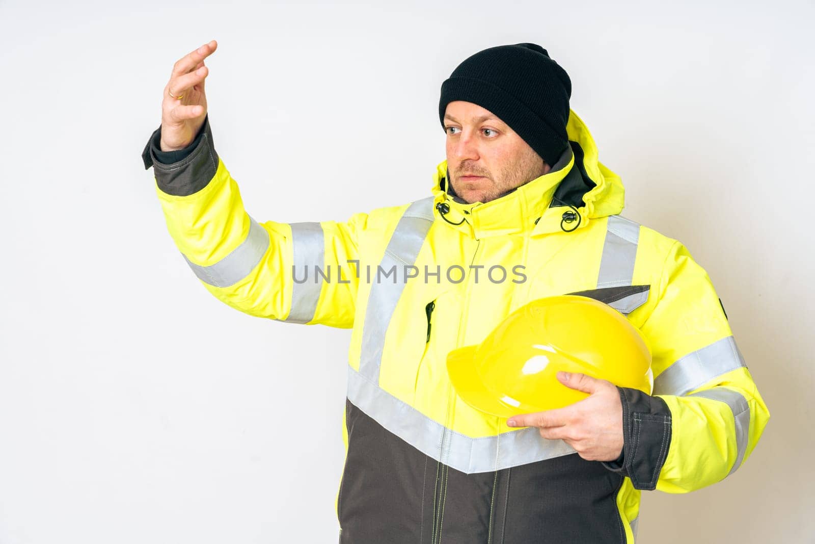 a man wearing a yellow working winter jacket and a yellow safety helmet . High quality photo