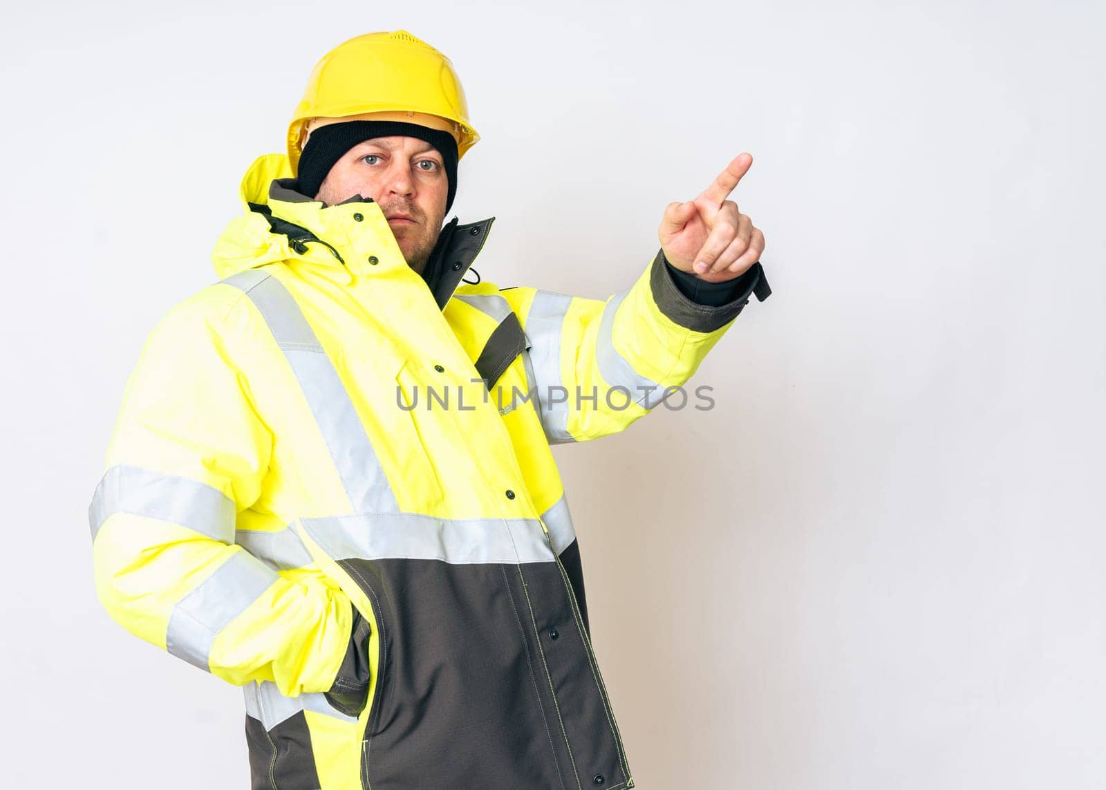 a man wearing a yellow working winter jacket and a yellow safety helmet . High quality photo